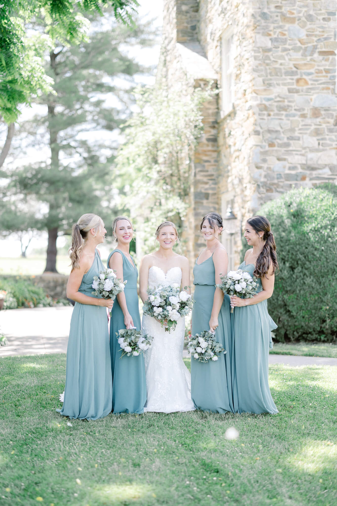 bride laughing with her bridesmaids on the lawn