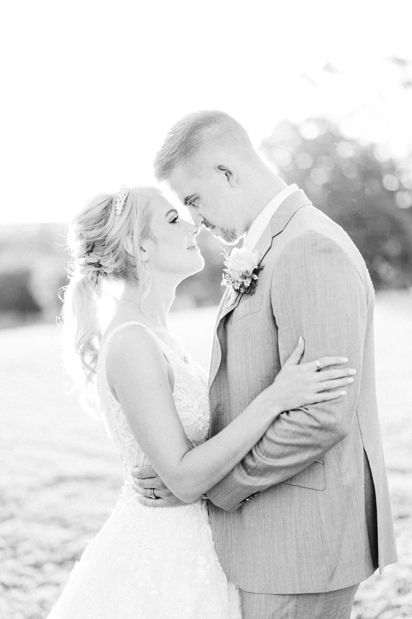 bride and groom touching noses in a field at the Olde Brenton Inn