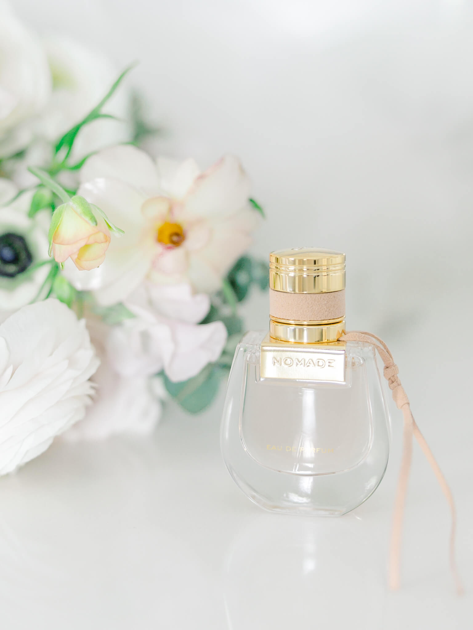 A close up of Chloe's perfume Nomade with wedding flowers.