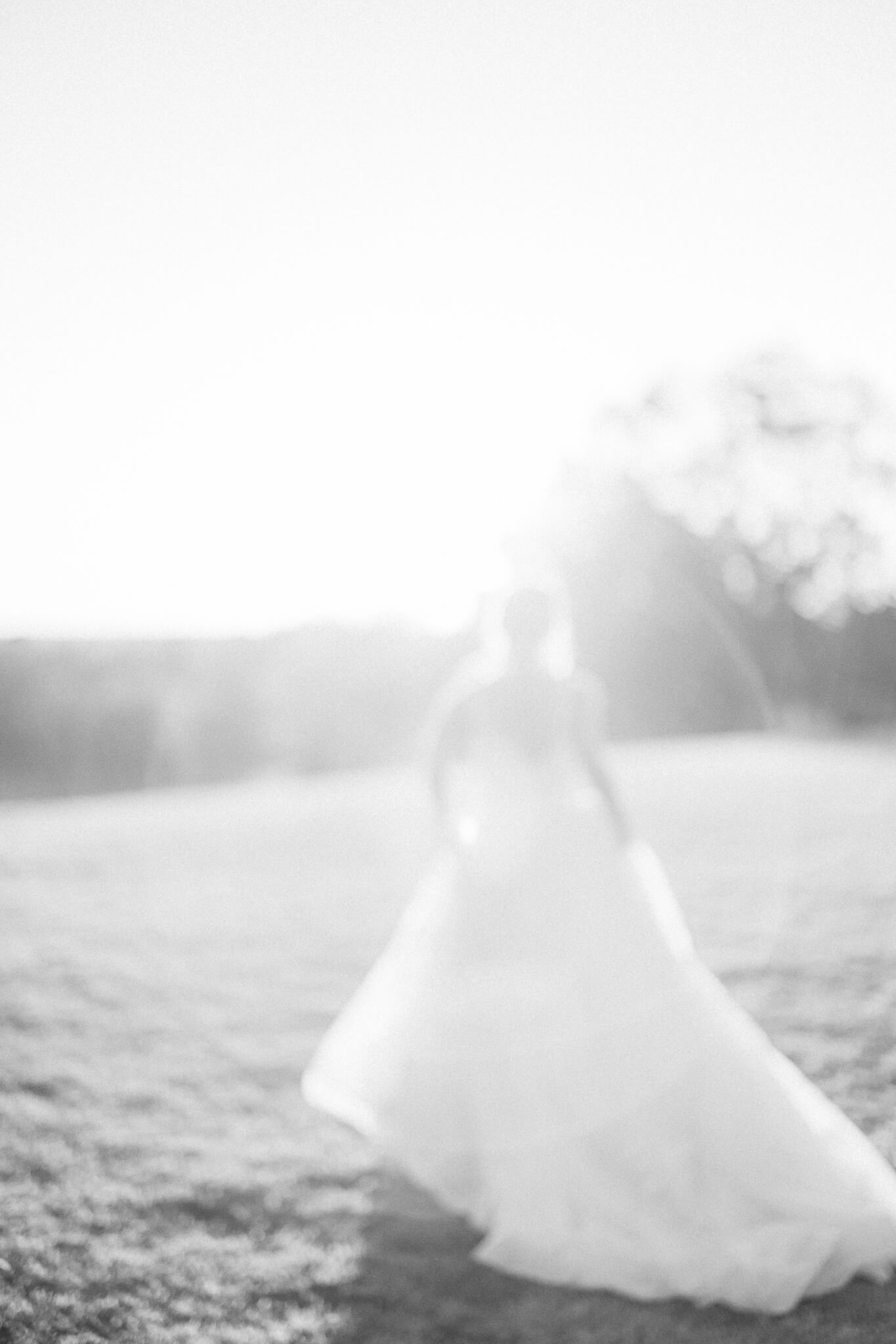 blurry fine art photograph of bride running towards sunset in princess dress