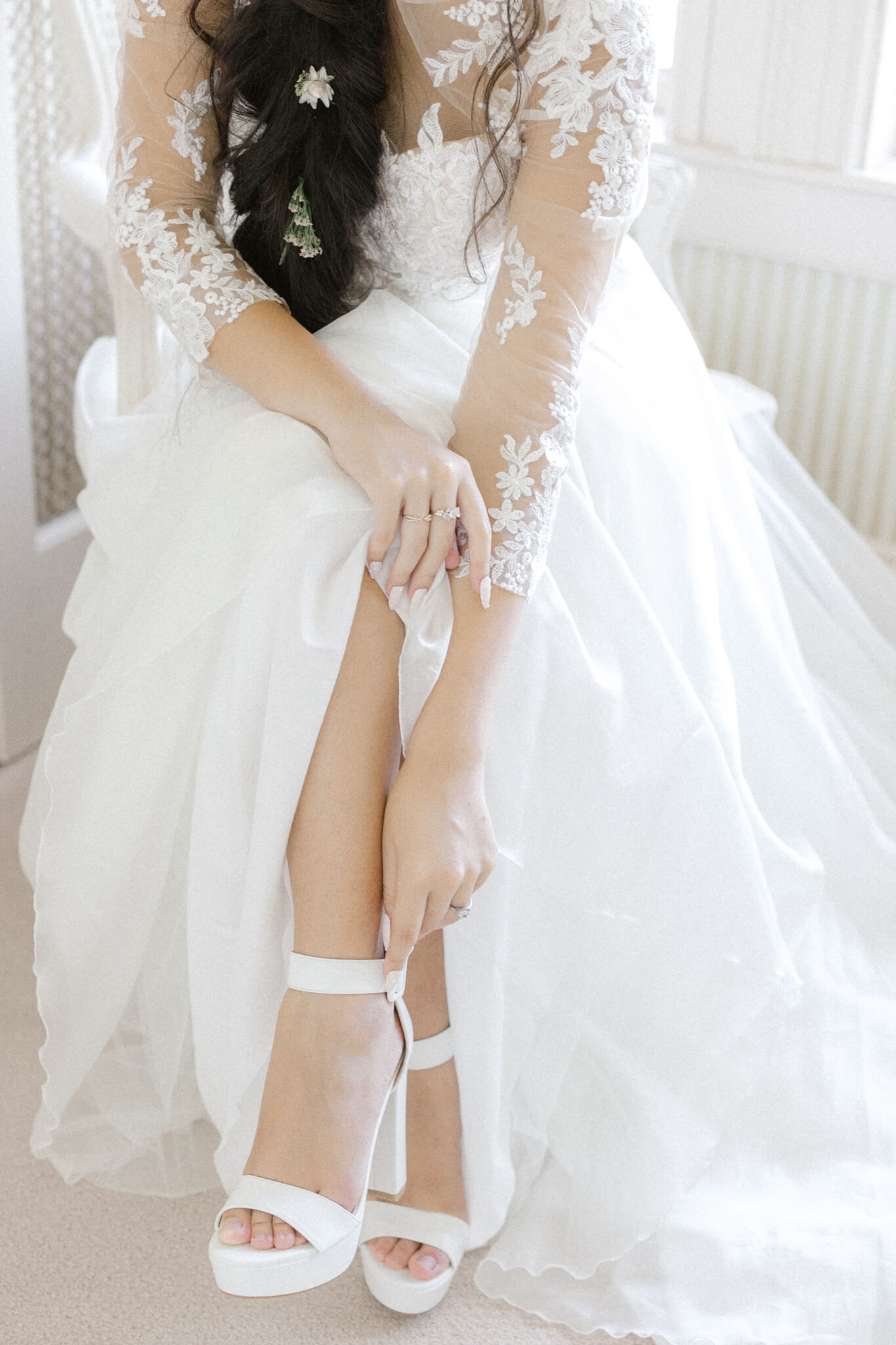 bride in lace wedding dress putting on her shoes