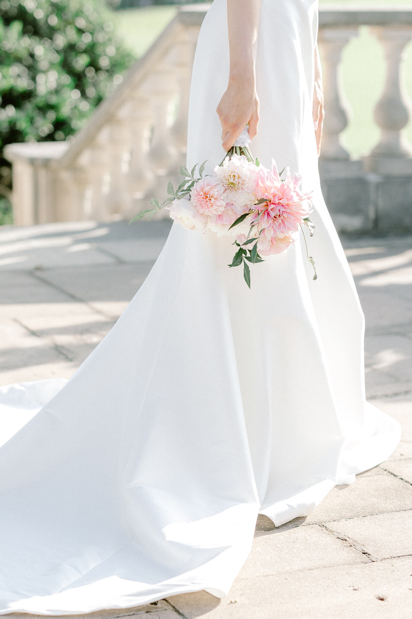 bride in white dress walking and holding pink and white bouquet