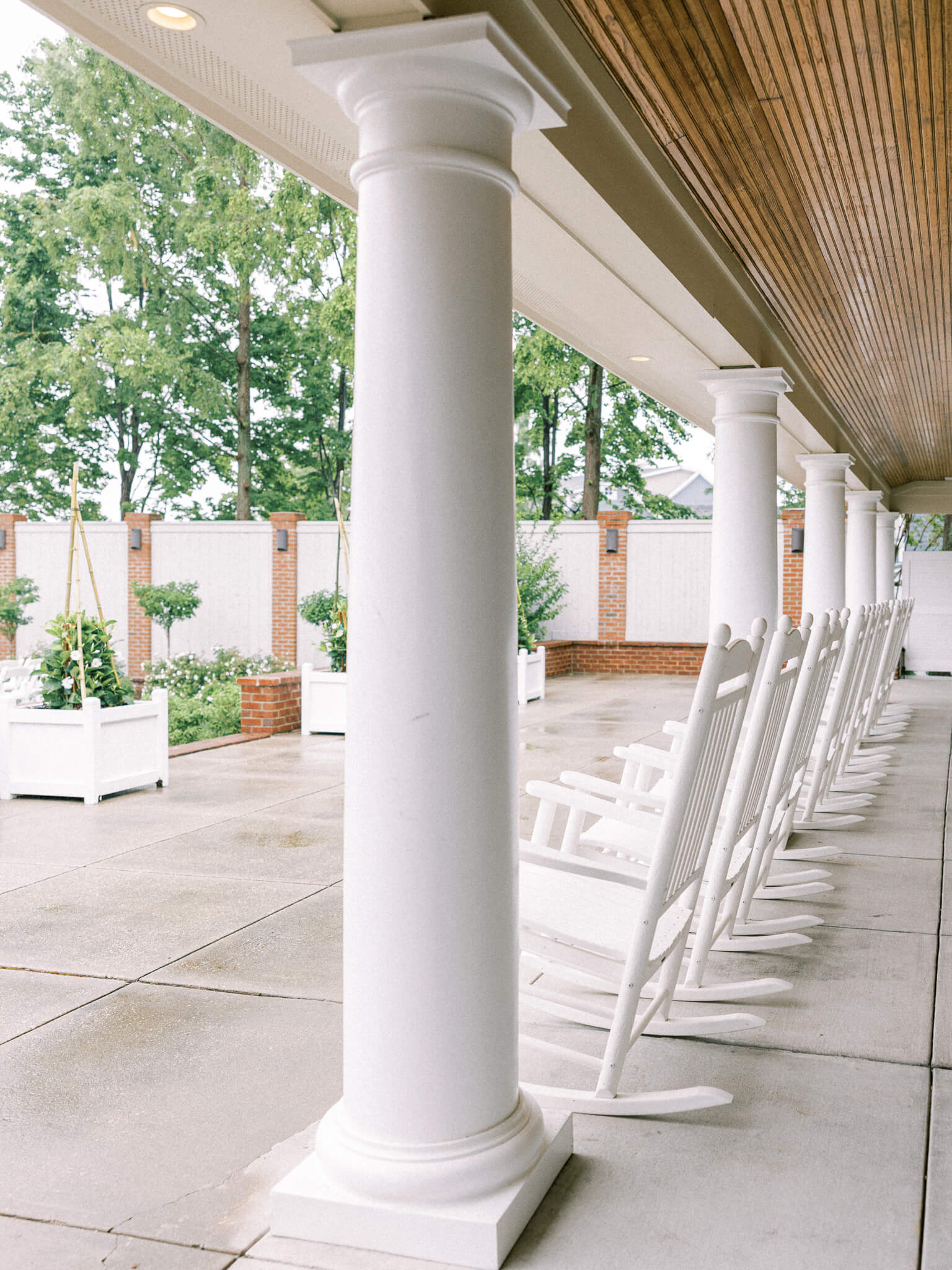White rocking chairs under the covered back porch of Chesapeake Bay Beach club overlooking the outdoor ceremony space