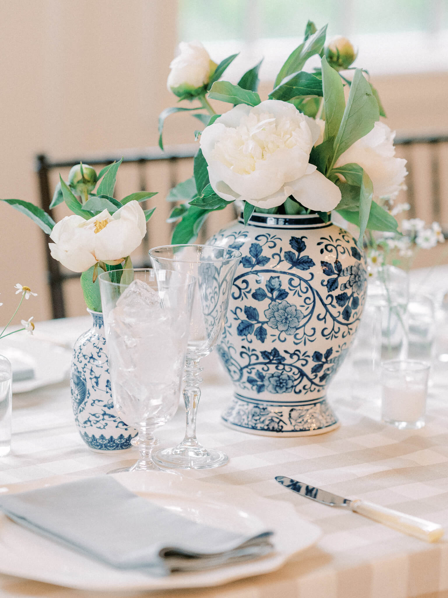 Closeup tablescape with a gingham table cloth and blue chinoiserie vases and white flowers