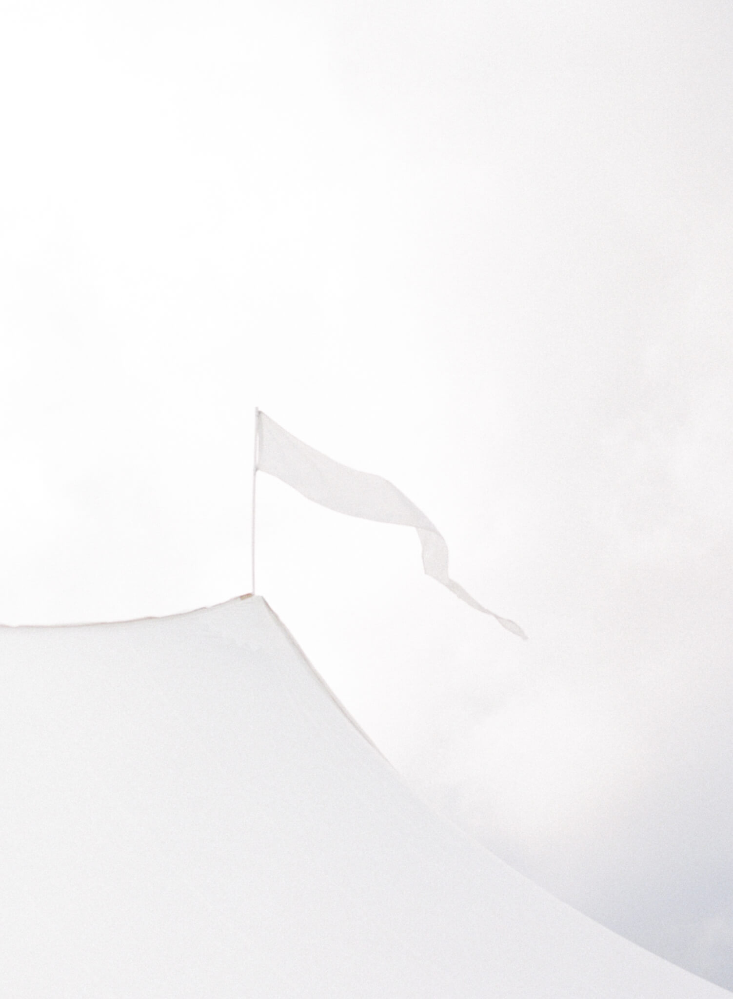 Closeup of a flag on a white sailcloth tent.