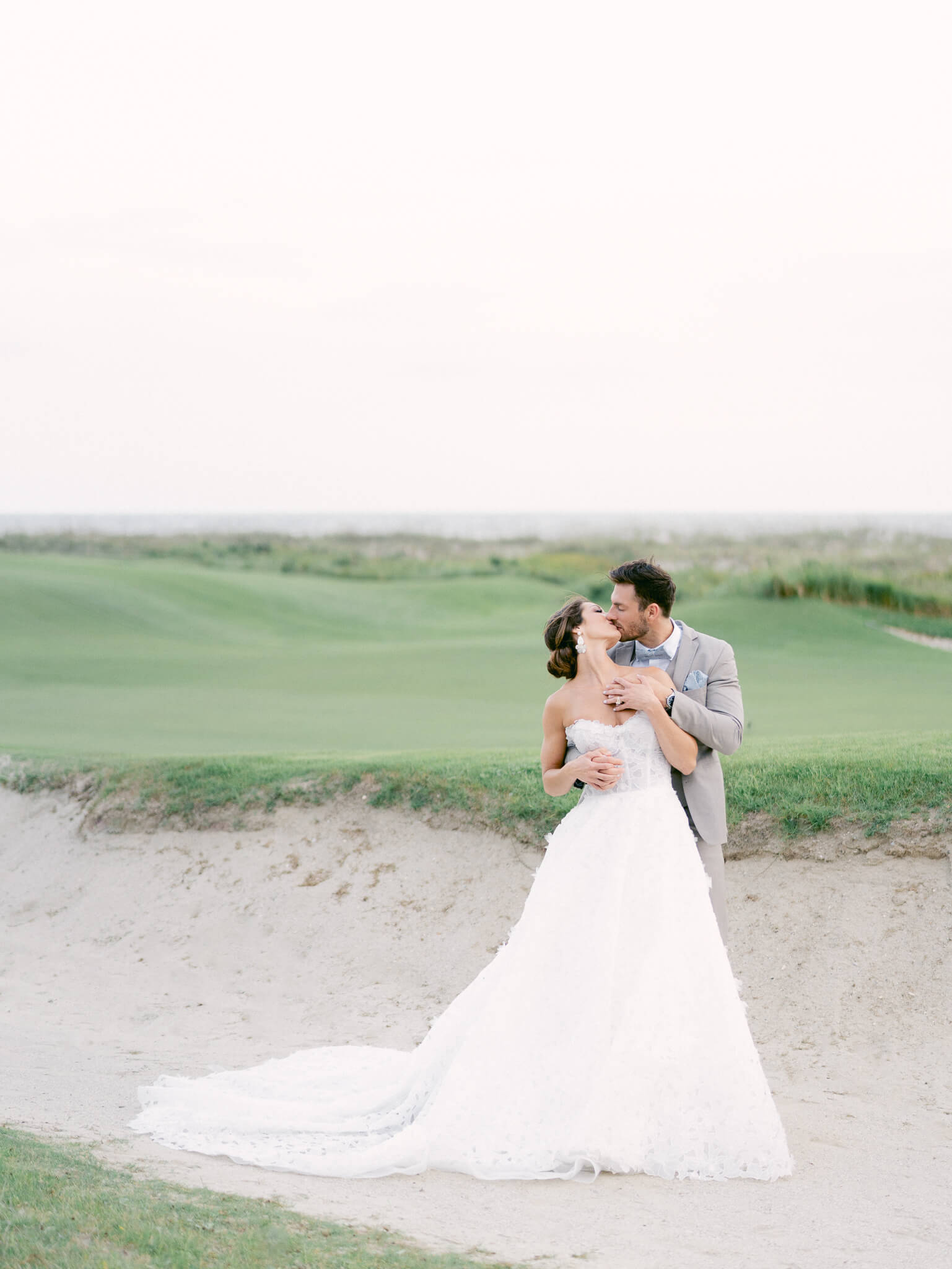 A bride and groom kissing on the Kiawah Island Ocean Course.