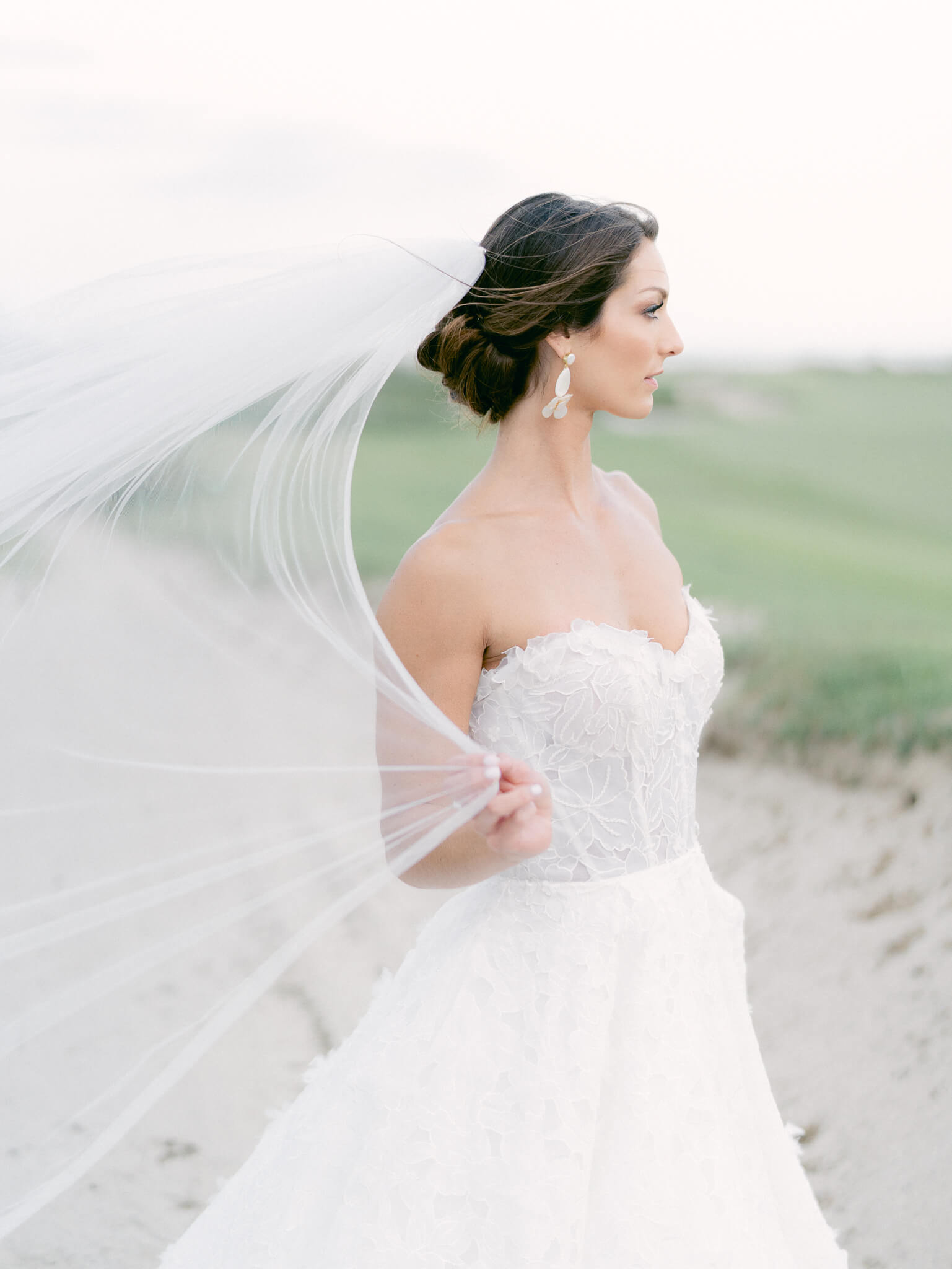 Profile of a bride holding her veil in the wind and looking off into the distant Atlantic ocean on the Kiawah Island Golf Course.