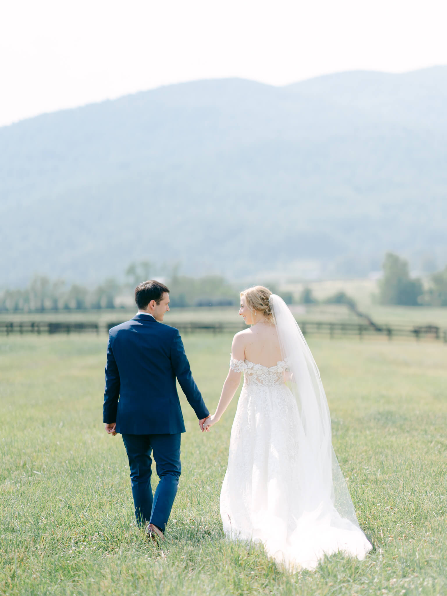 A bride and groom walking away hand in hand towards the Southern Virginia mountains.