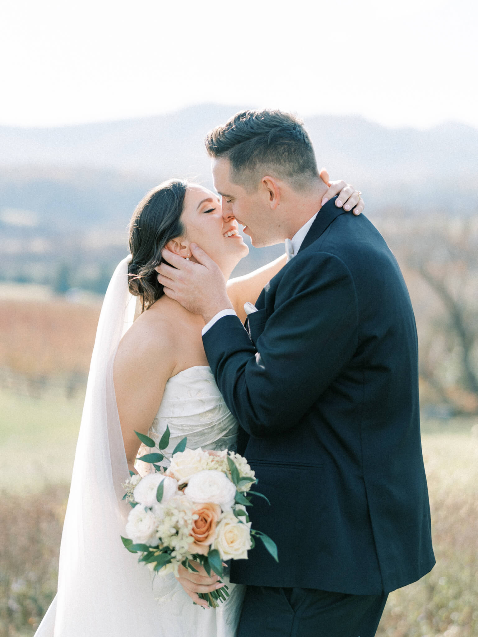 Closeup of a bride and groom kissing at a Pippin Hill wedding with the Blue Ridge Mountains in the background.