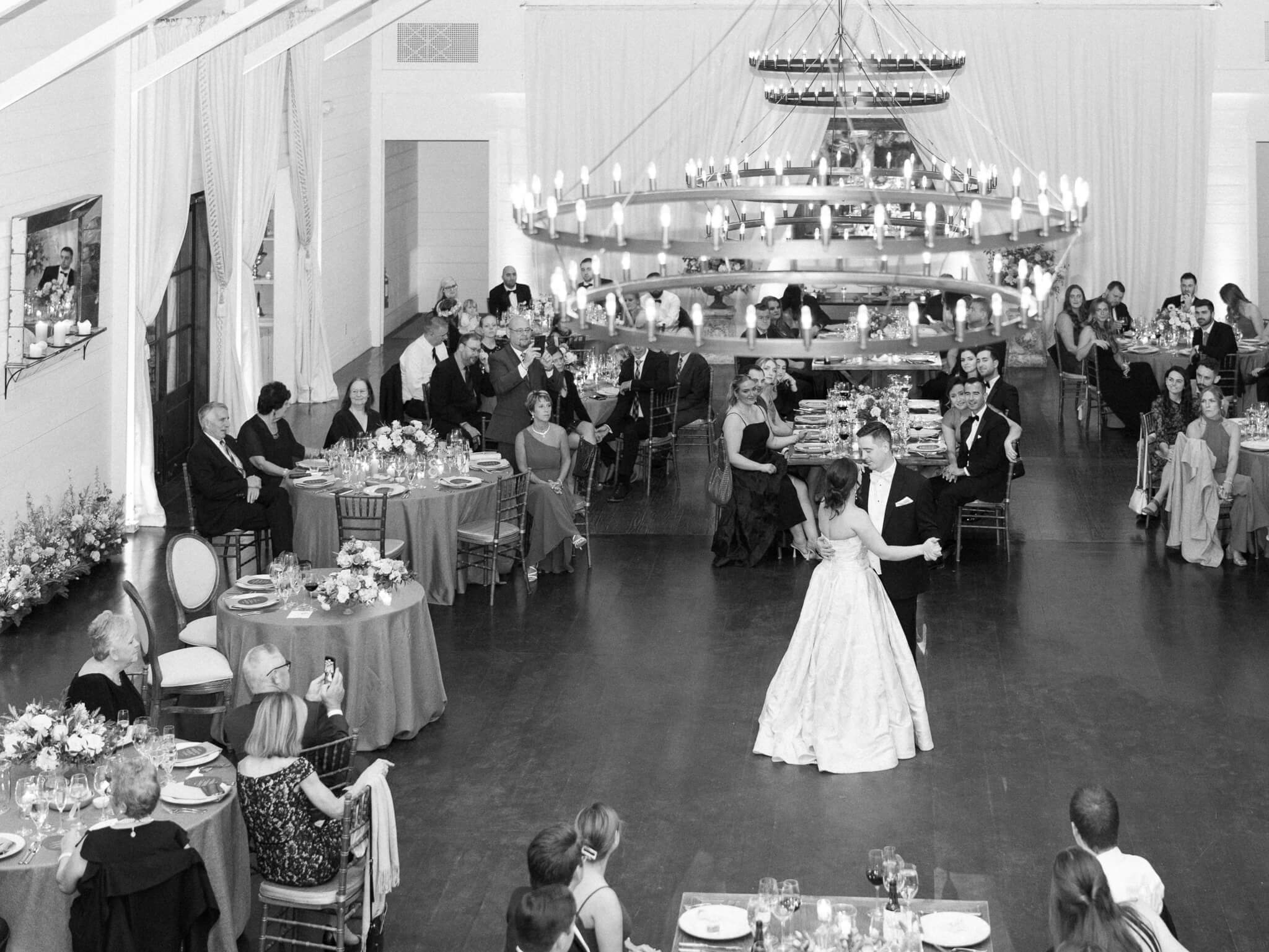 Black and white image of a newlywed couple sharing their first dance at their Pippin Hill wedding reception in the midst of their guests.