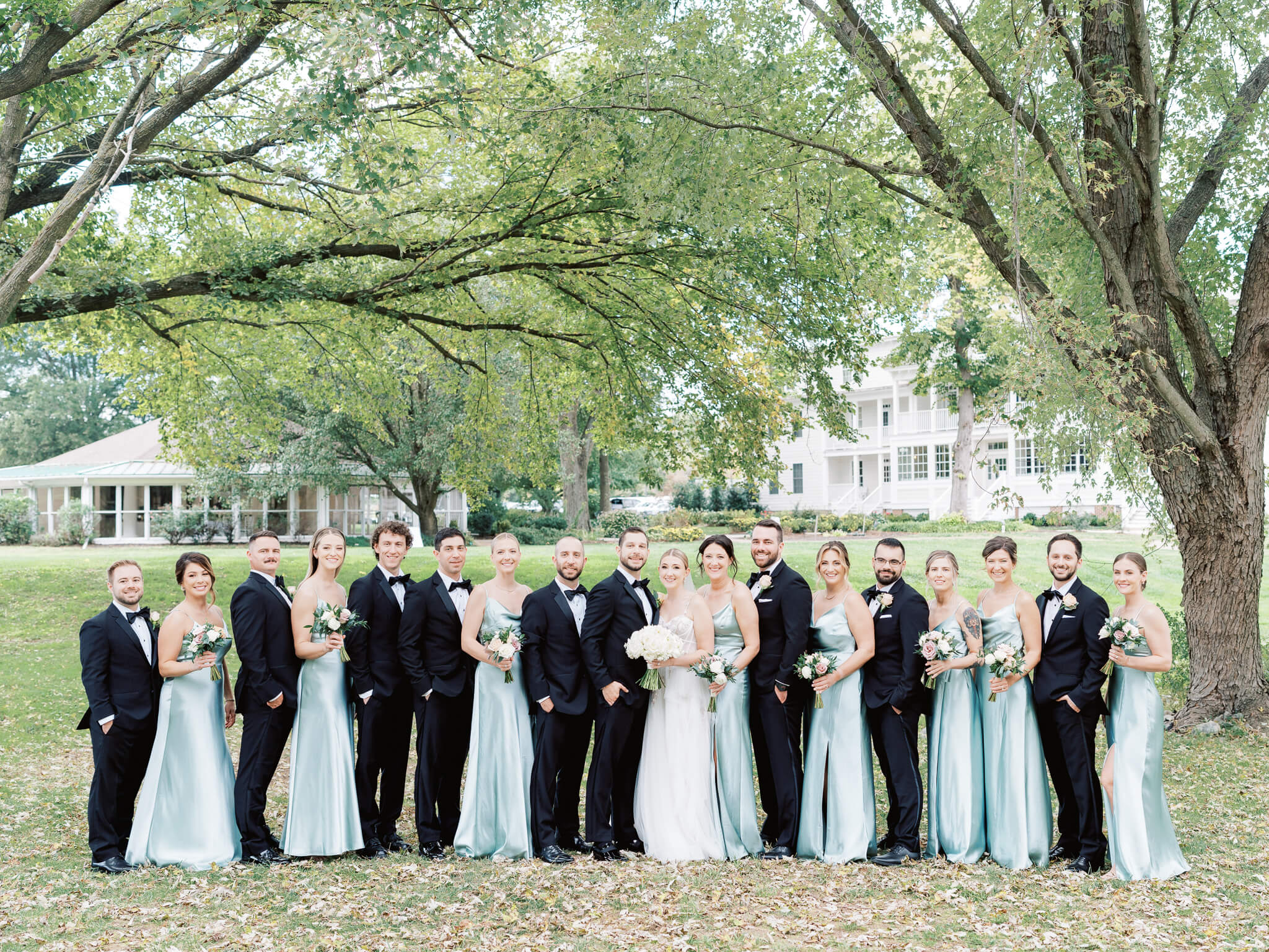 A full wedding party standing with the bride and groom in front of Kent Island Resort