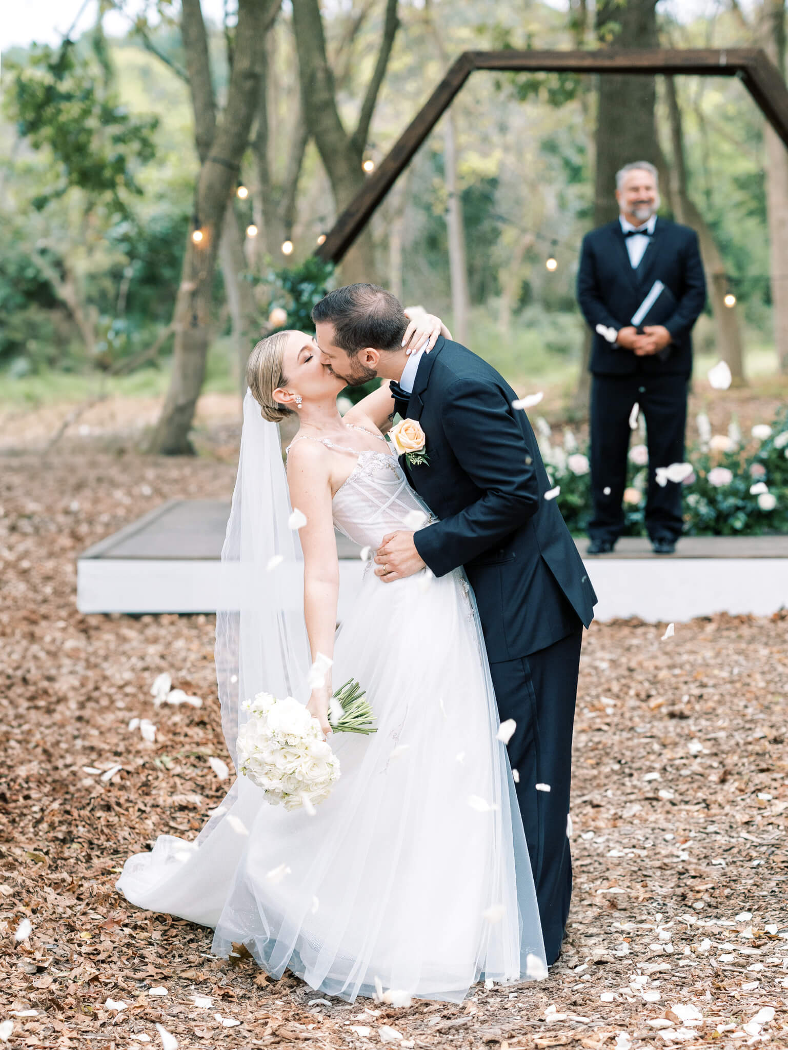 A bride and groom kissing at the altar nestled amongst the trees
