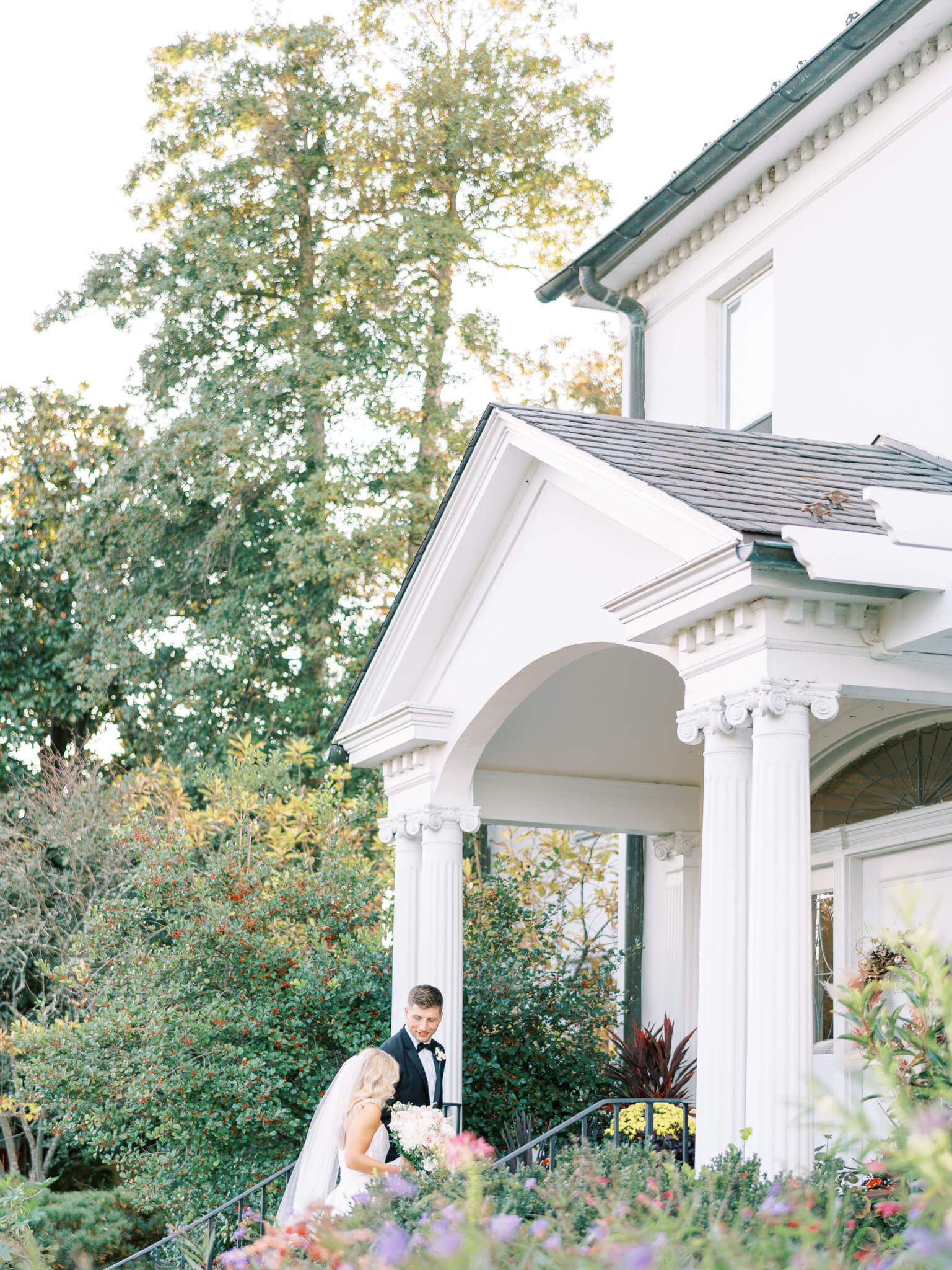 A bride and groom walking up the front steps of River Farm Wedding Venue.