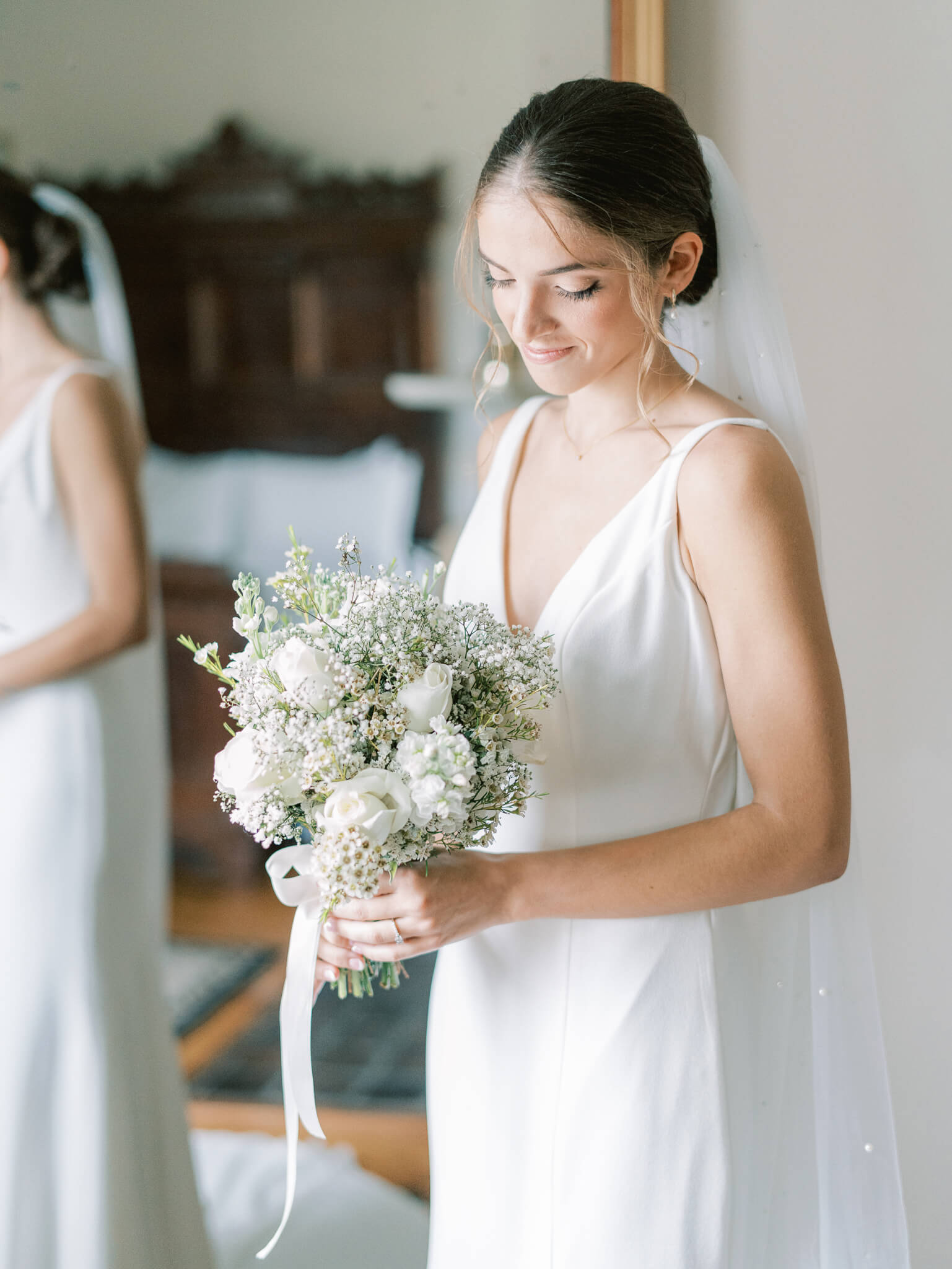 A bride looking down at her bouquet in the getting ready suite of Springfield Manor wedding venue.