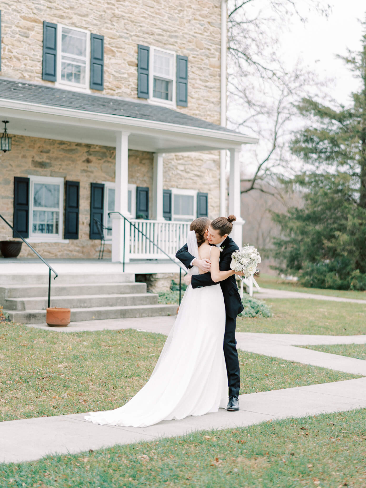 A groom embracing his bride during their first look in front of Springfield Manor.