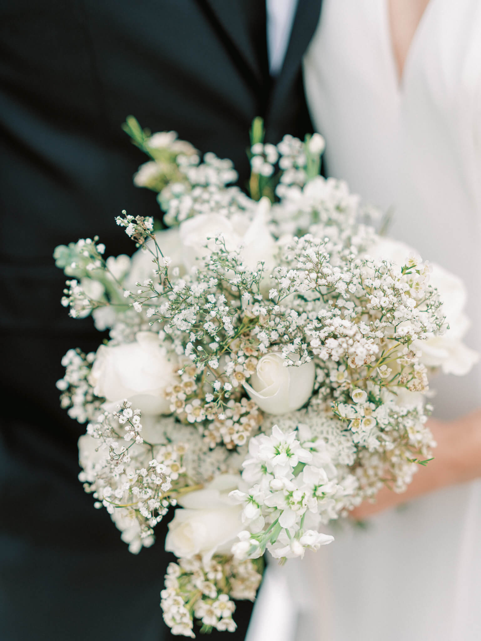 Close-up of a bridal bouquet made of roses and baby's breath.