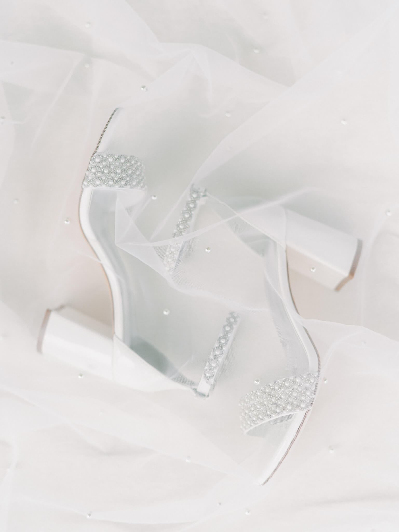 The bride's pearled wedding heels laying under her veil.