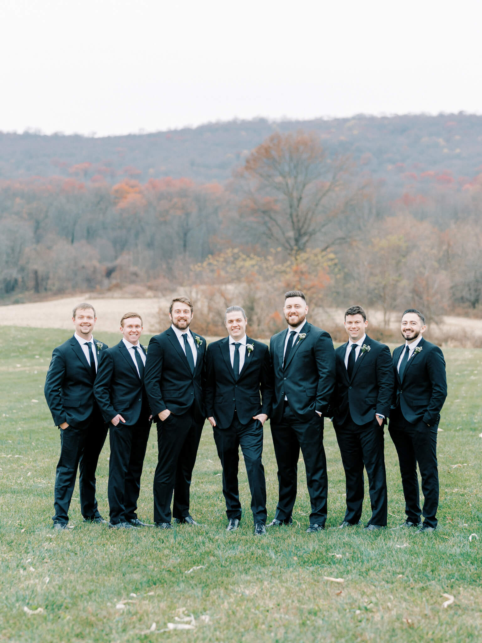 A groom and his groomsmen in black suits in front of a mountainous background.
