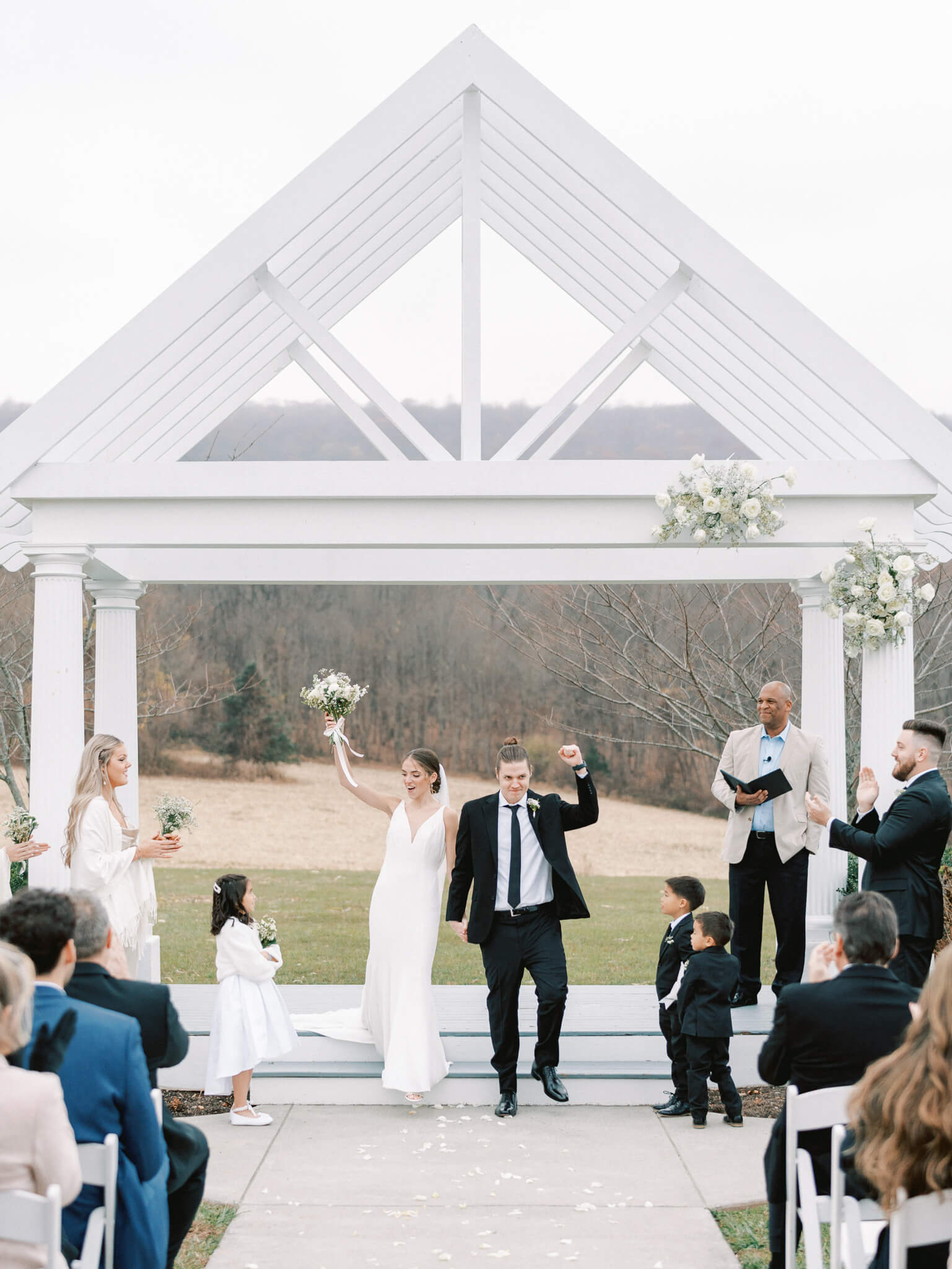 A bride and groom cheering in front of their guests and walking down the aisle after being pronounced husband and wife.