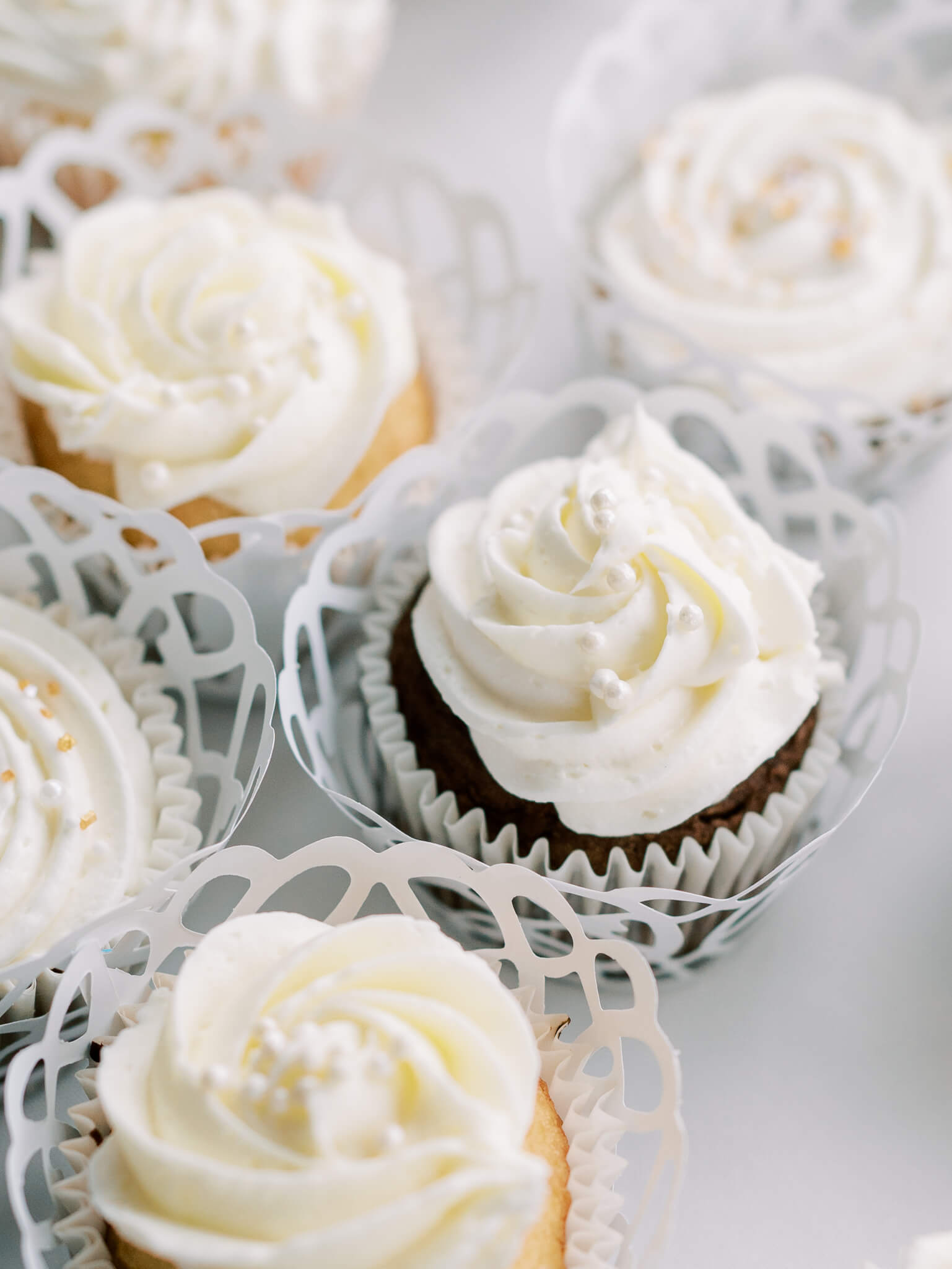 Close-up of chocolate and vanilla cupcakes with white icing in lace paper.