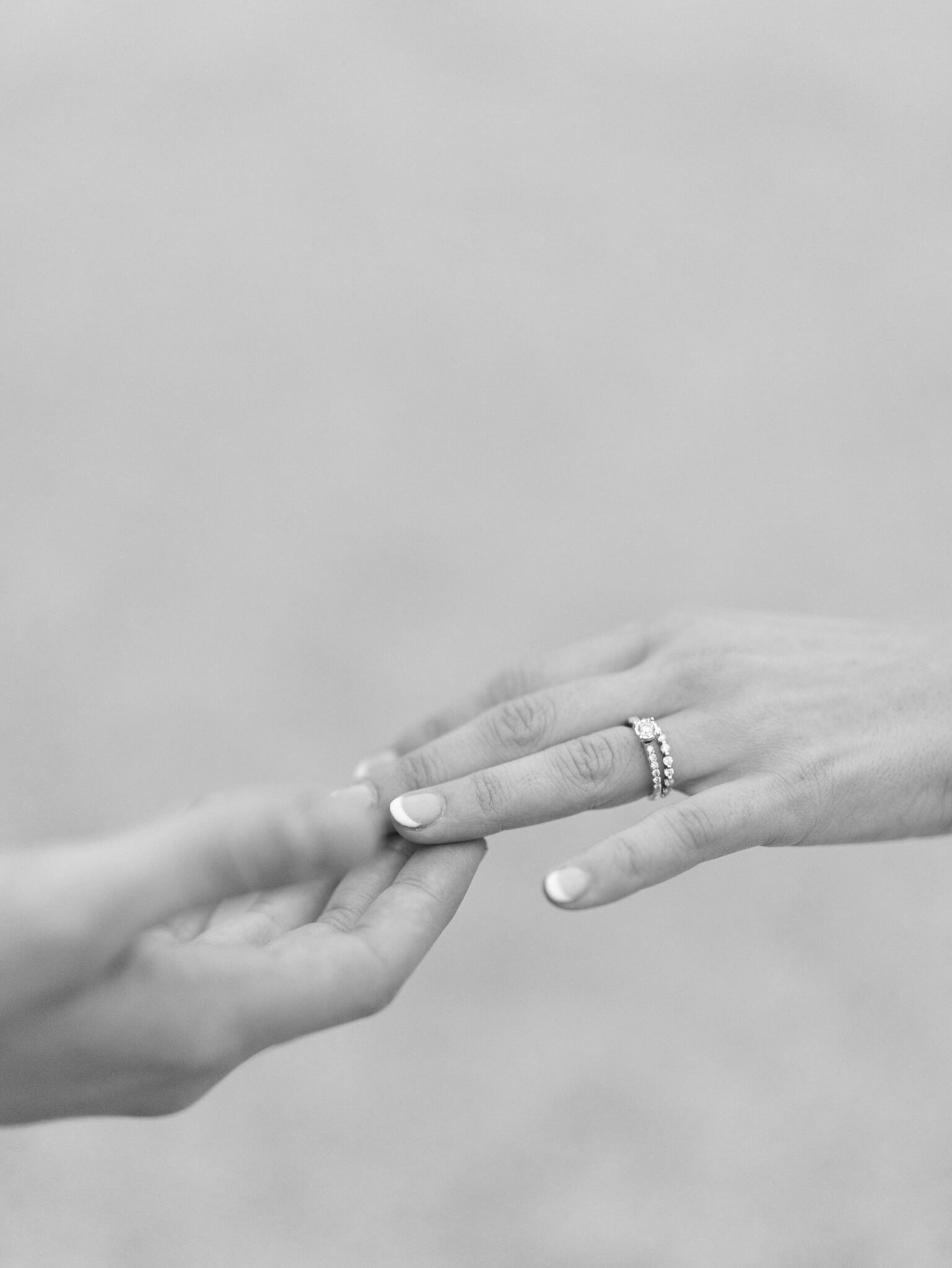 A close-up black and white image of the bride and groom's hands.