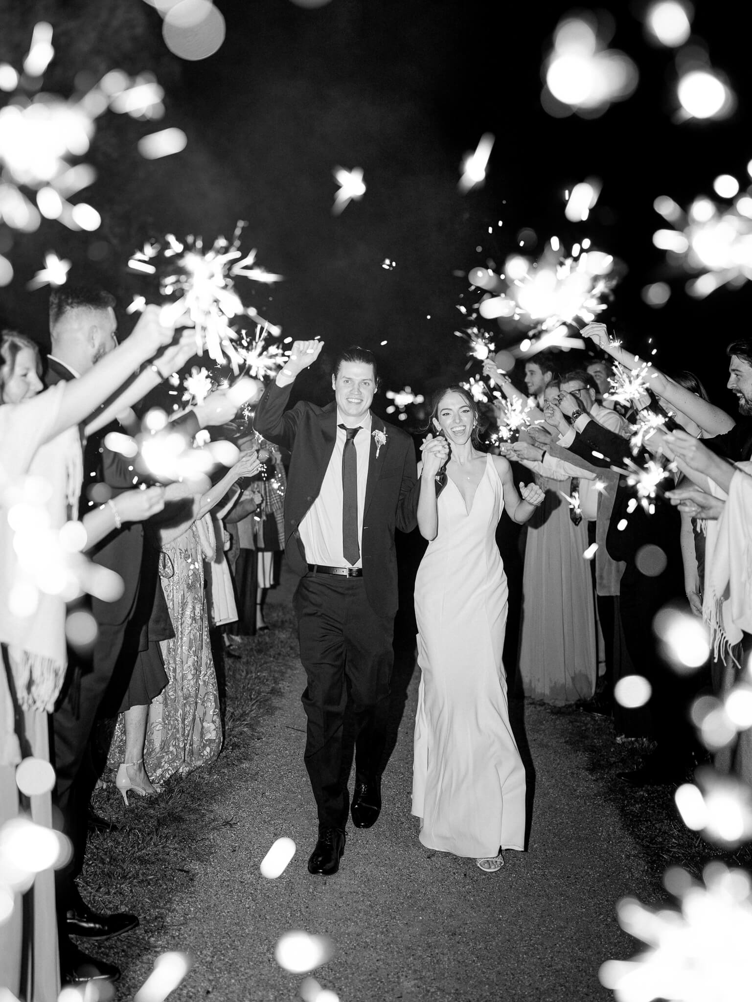 A black and white sparkler exit with the bride and groom cheering and walking through their guests.