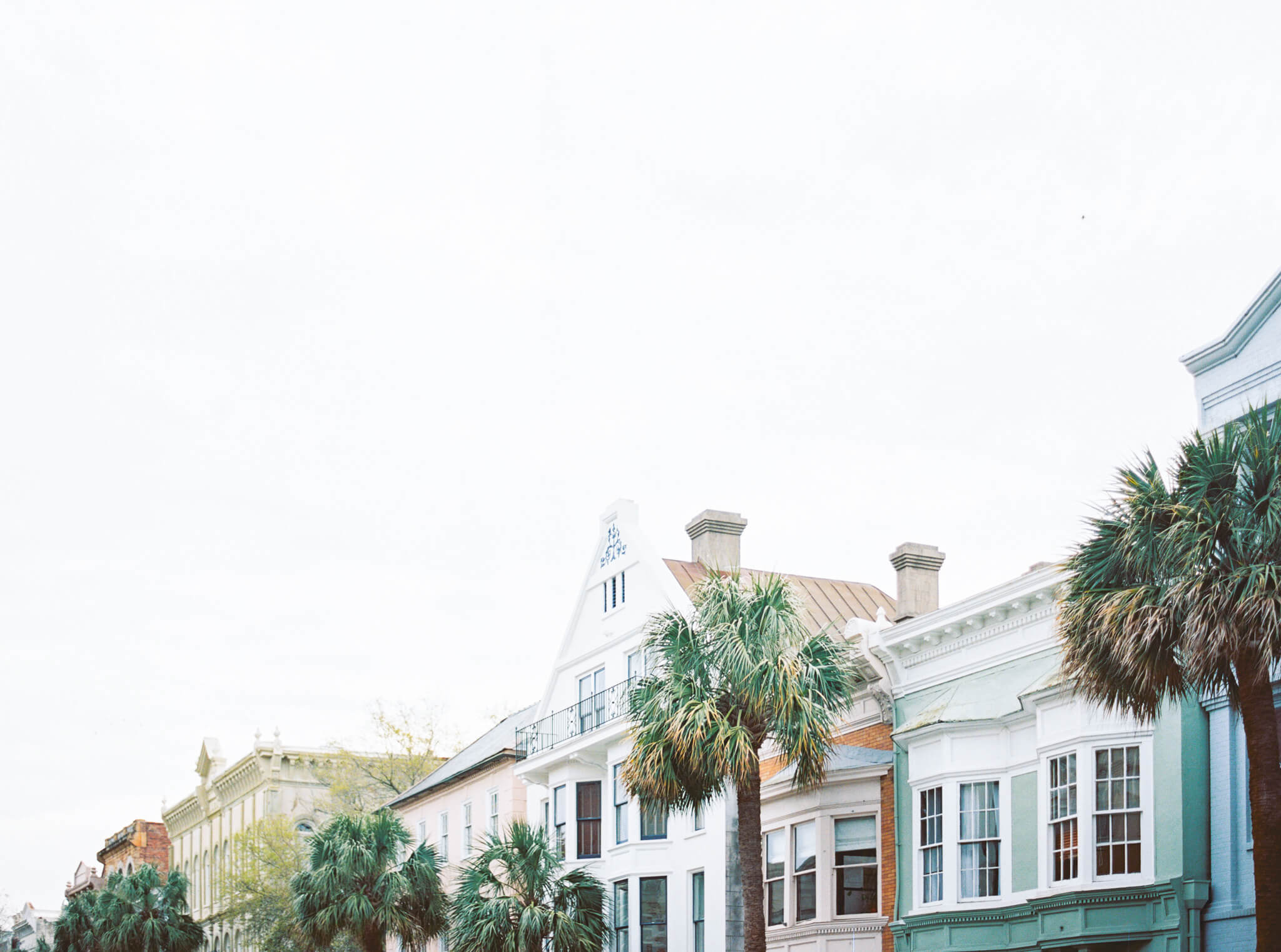A row of colorful houses with palm trees in Charleston.