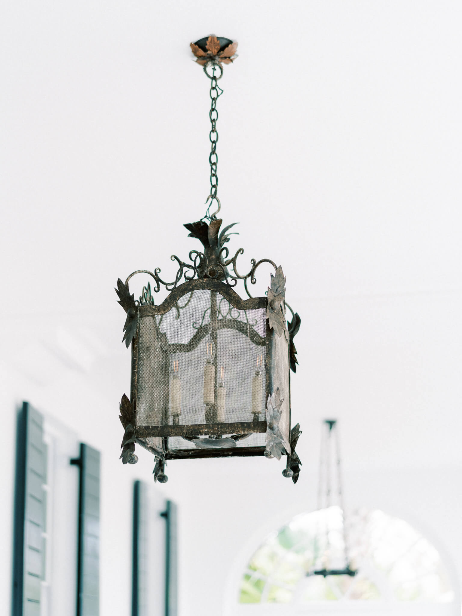An iron light fixture hanging at Lowndes Grove Wedding Venue's covered porch entry.