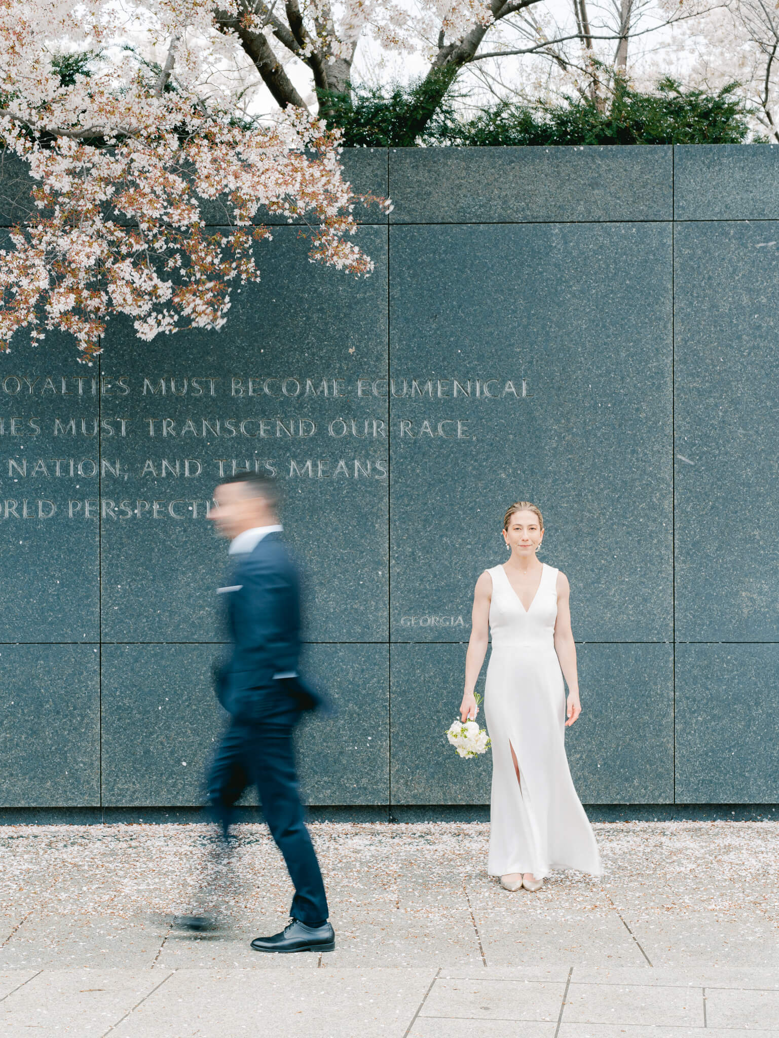 A blurry shot of a groom walking past his bride under the cherry blossoms at the MLK memorial in Washington, D.C.