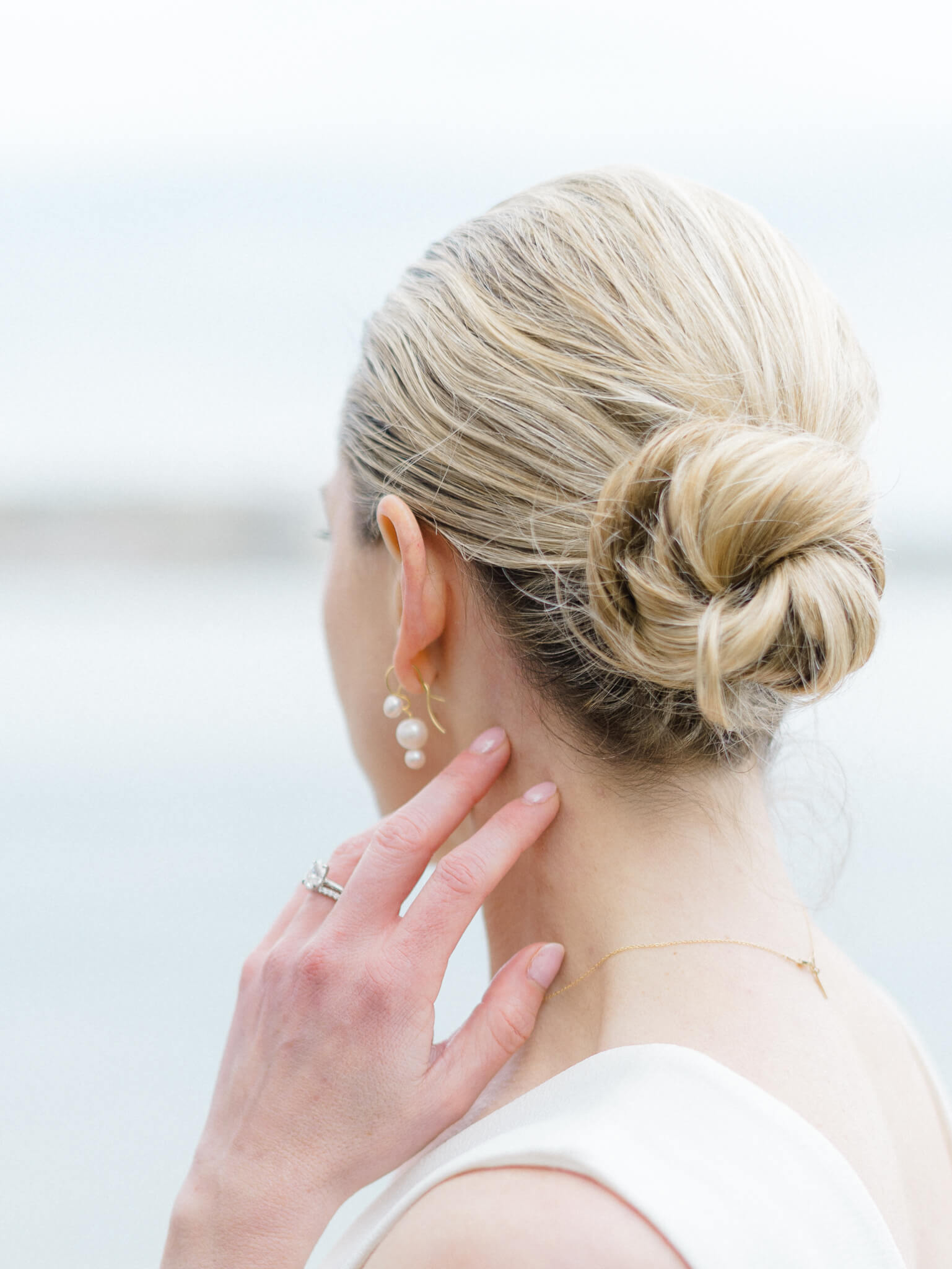 The back of the head of a bride, showing her wedding updo while she touches her neck and looks out over the Tidal Basin
