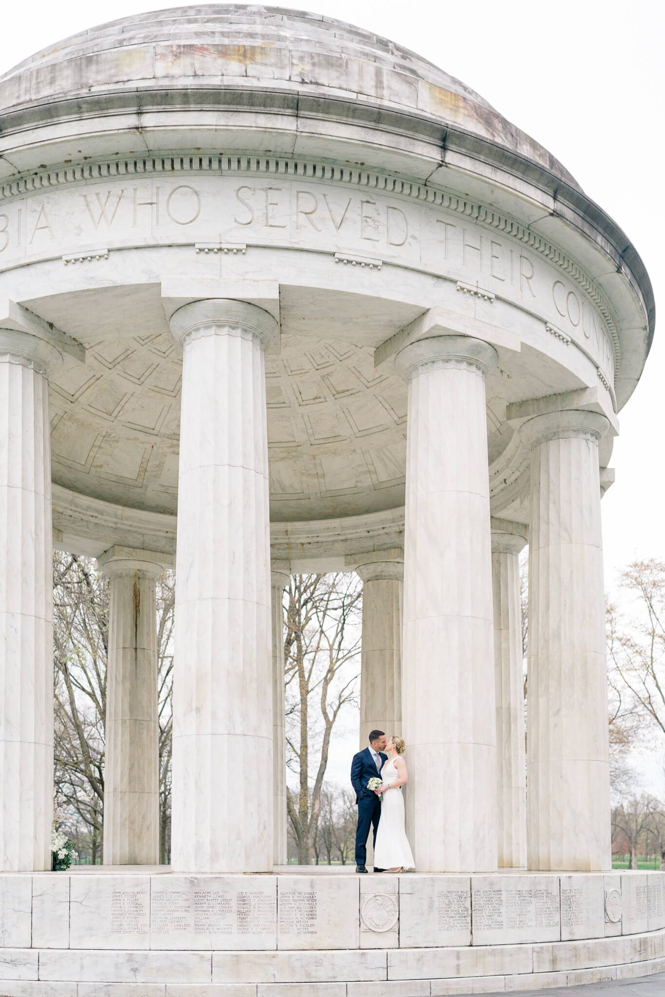 A bride and groom kissing at the D.C. War Memorial during their cherry blossom elopement