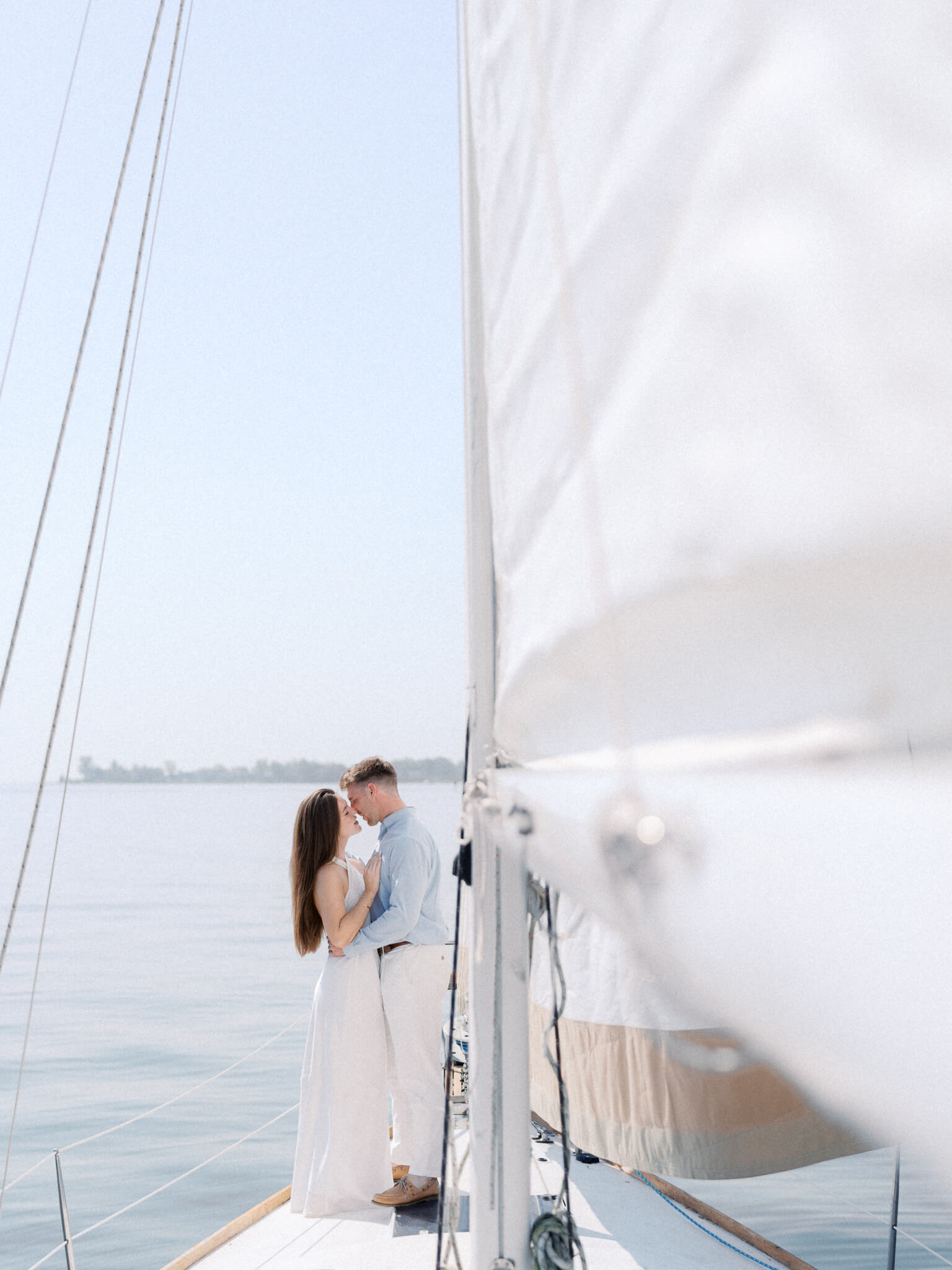 A man and woman leaning in for a kiss on a sailboat engagement session.