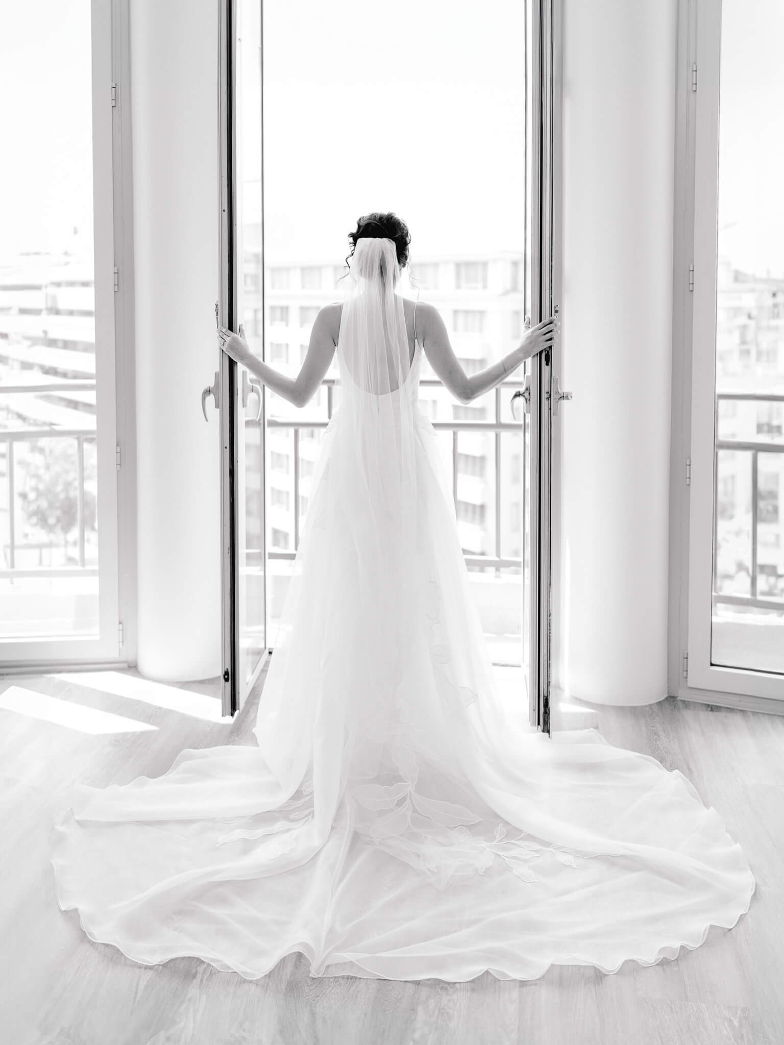 Black and white image of a bride looking out the window at the Westin, Georgetown.