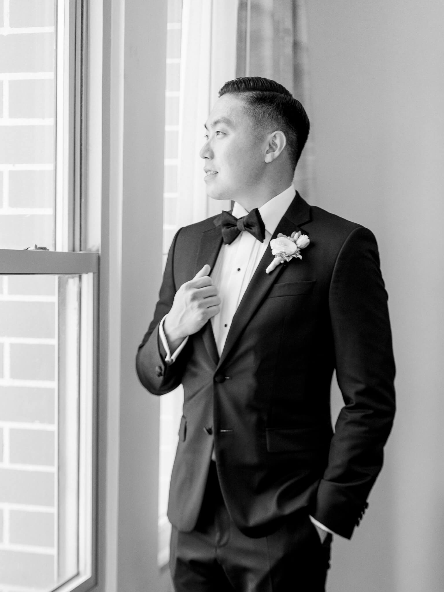 Black and white image of a groom looking out the window in his tux at his Westin Georgetown Wedding.