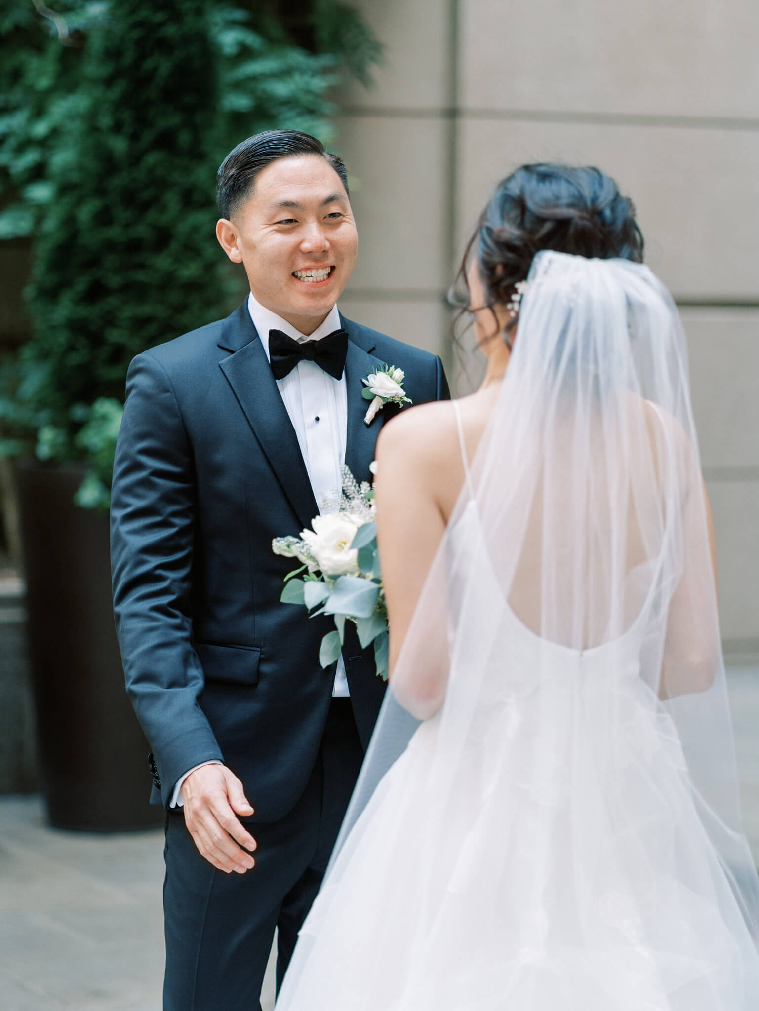 A groom in a tux seeing his bride for the first time during their first look at their Westin Georgetown Wedding.