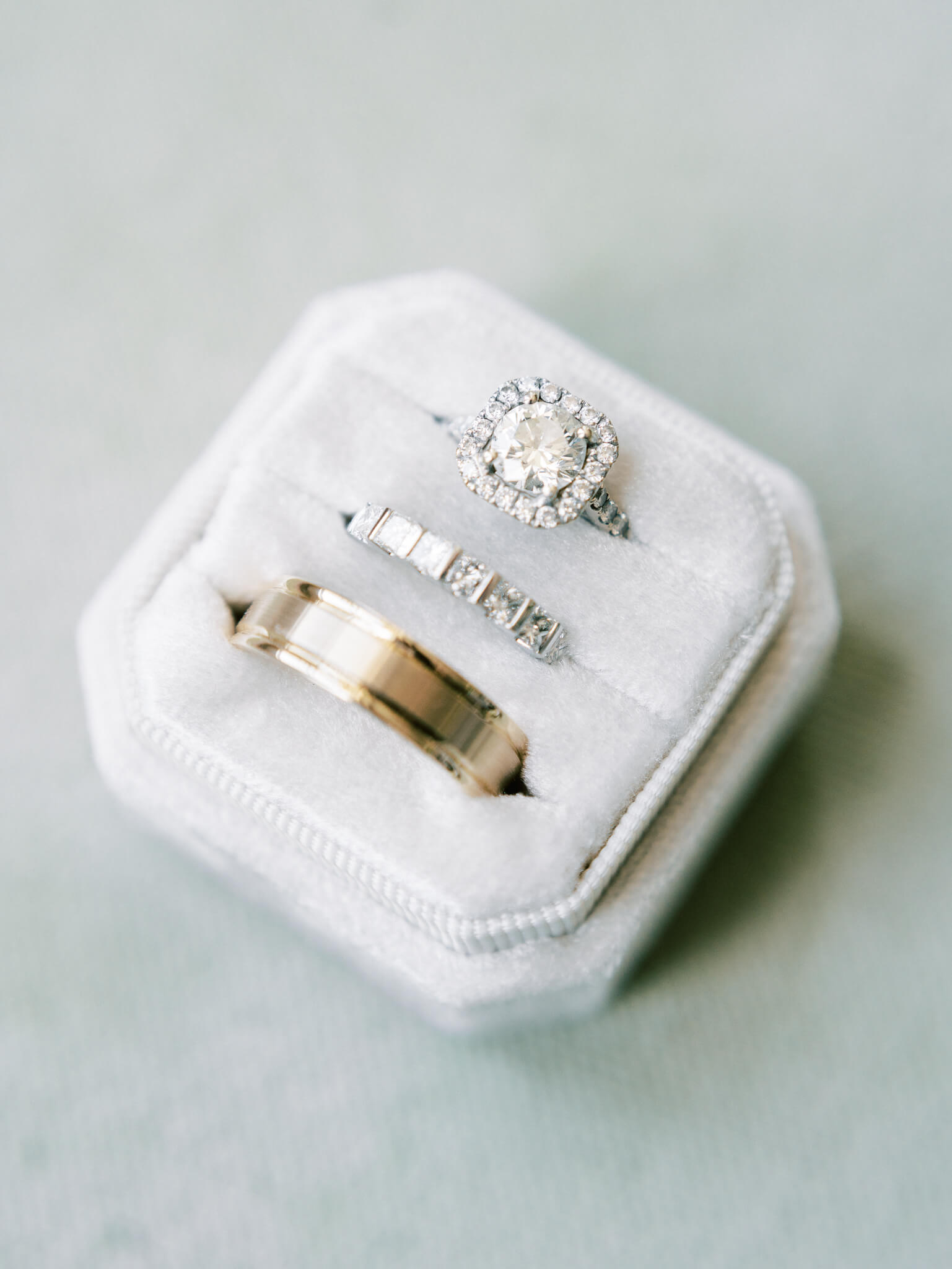 Closeup of a white ring box with three wedding rings inside.