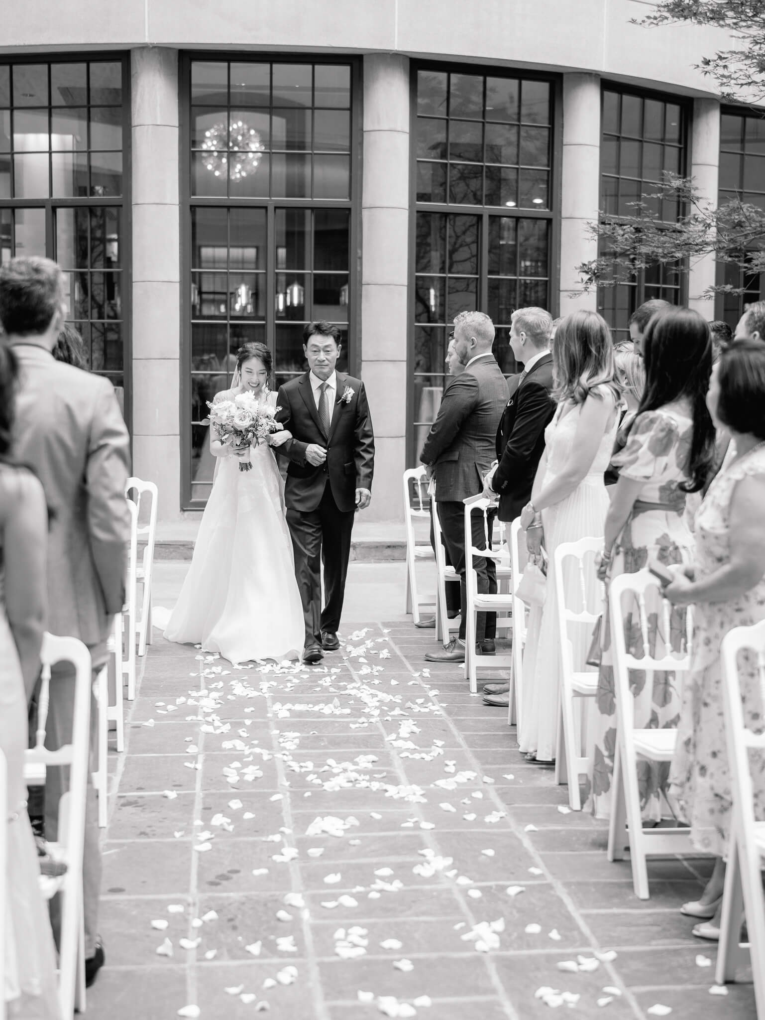 Black and white image of a bride and her father walking down the aisle during the ceremony at the Westin in Georgetown.