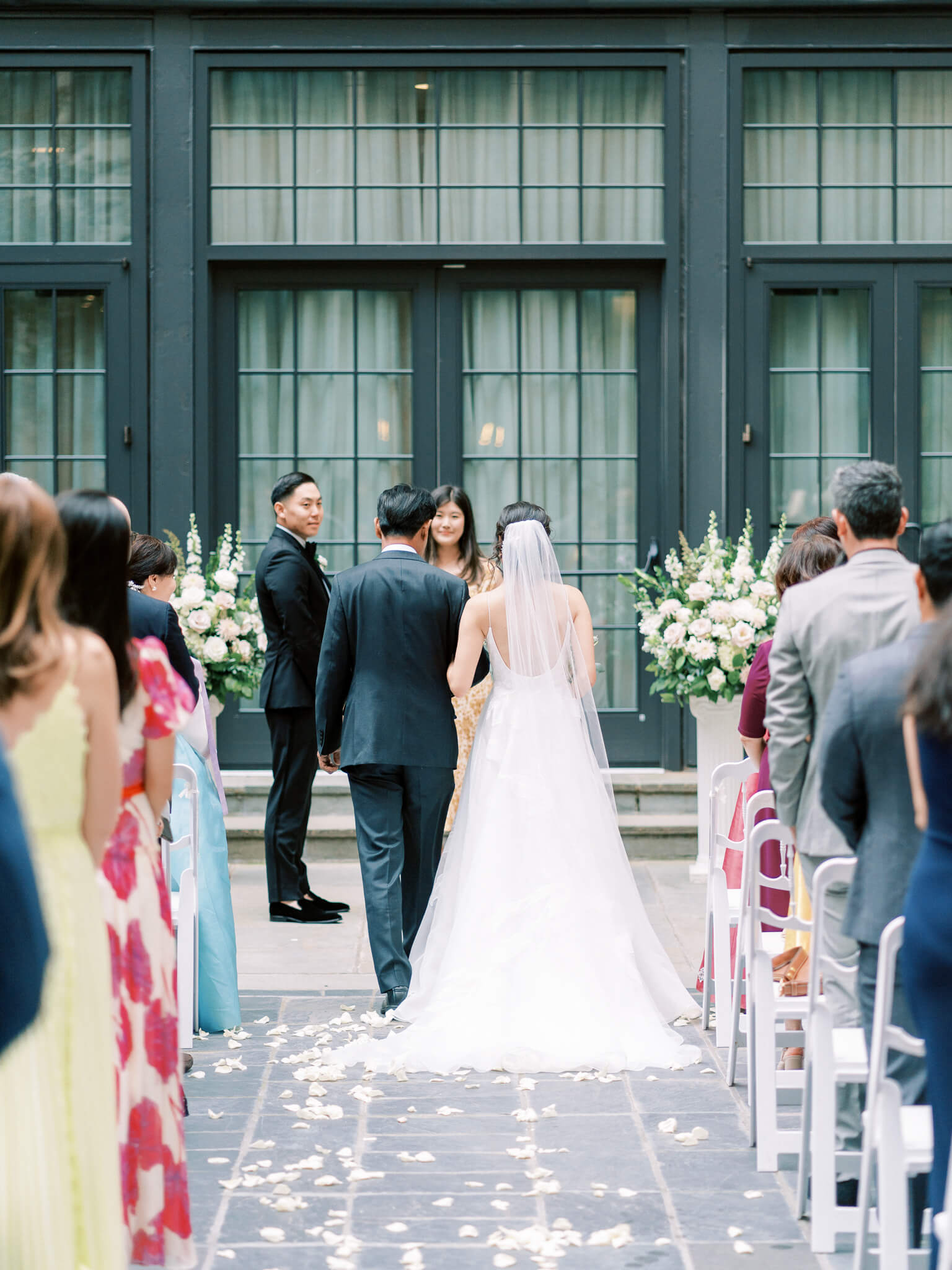 Image of the back of a bride walking down the aisle with her father towards her groom at their Westin Georgetown Wedding.