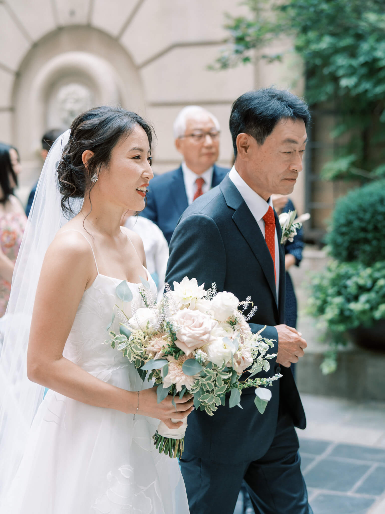 Closeup image of a bride and her father walking down the aisle at the beginning of the ceremony.