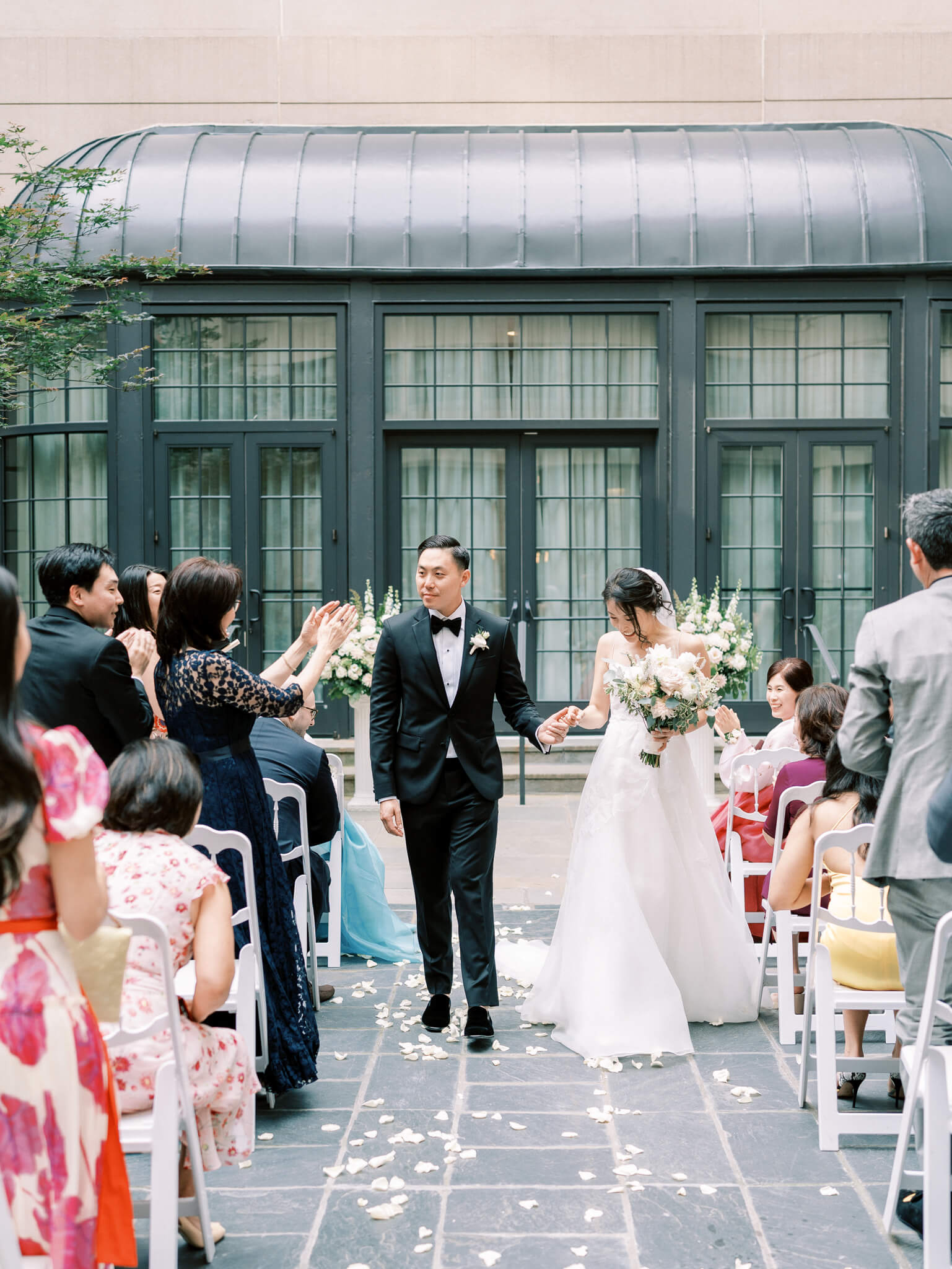 A bride and groom walking down the aisle after their ceremony in the courtyard while their guests cheer at a Westin Georgetown Wedding.