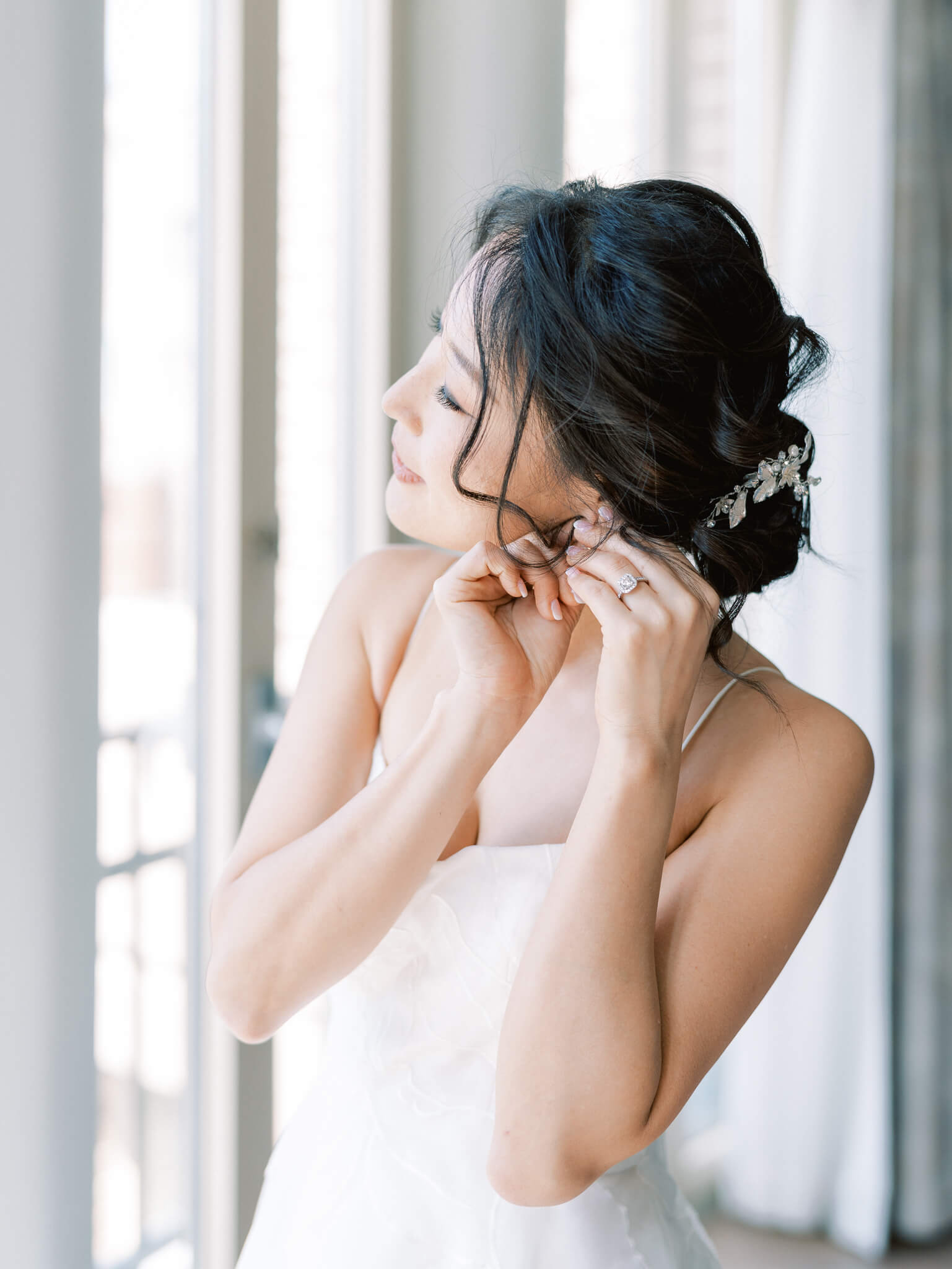 Closeup of a bride looking out the window and putting in her earring at her Westin Georgetown Wedding.