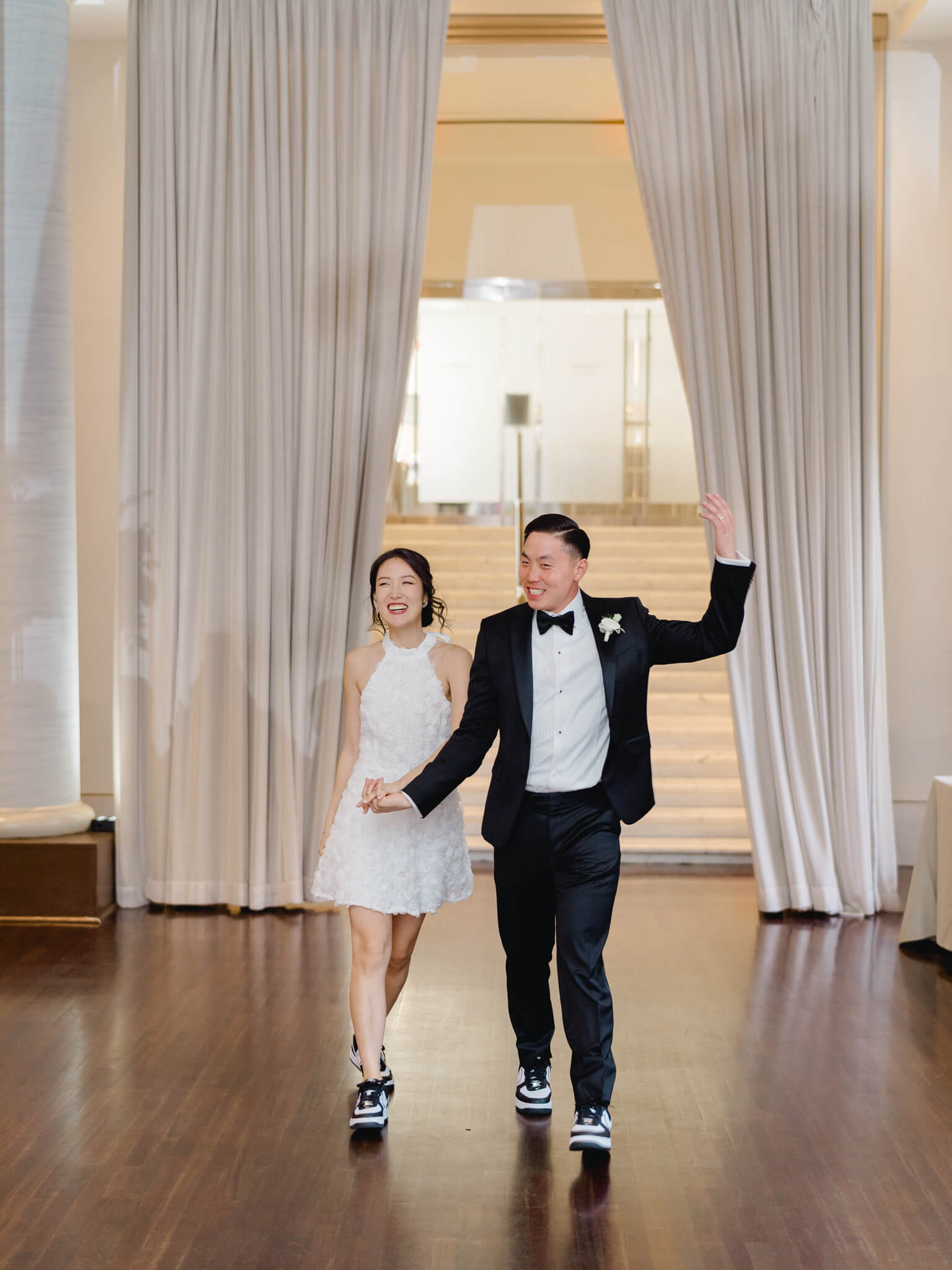 A bride and groom making their first entrance into their reception holding hands and smiling at their Westin Georgetown Wedding.