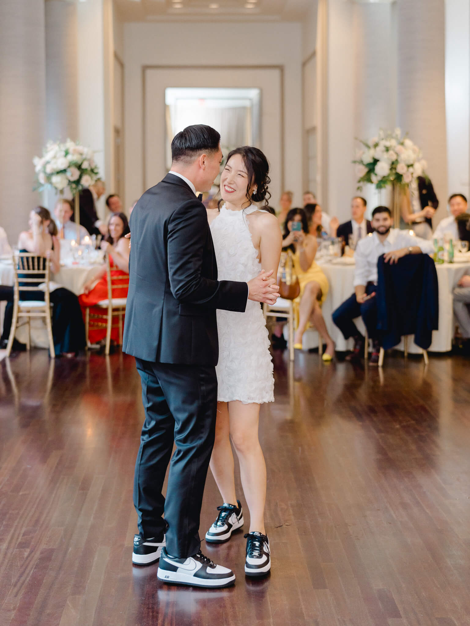 A bride and groom's first dance with their guests in the background.