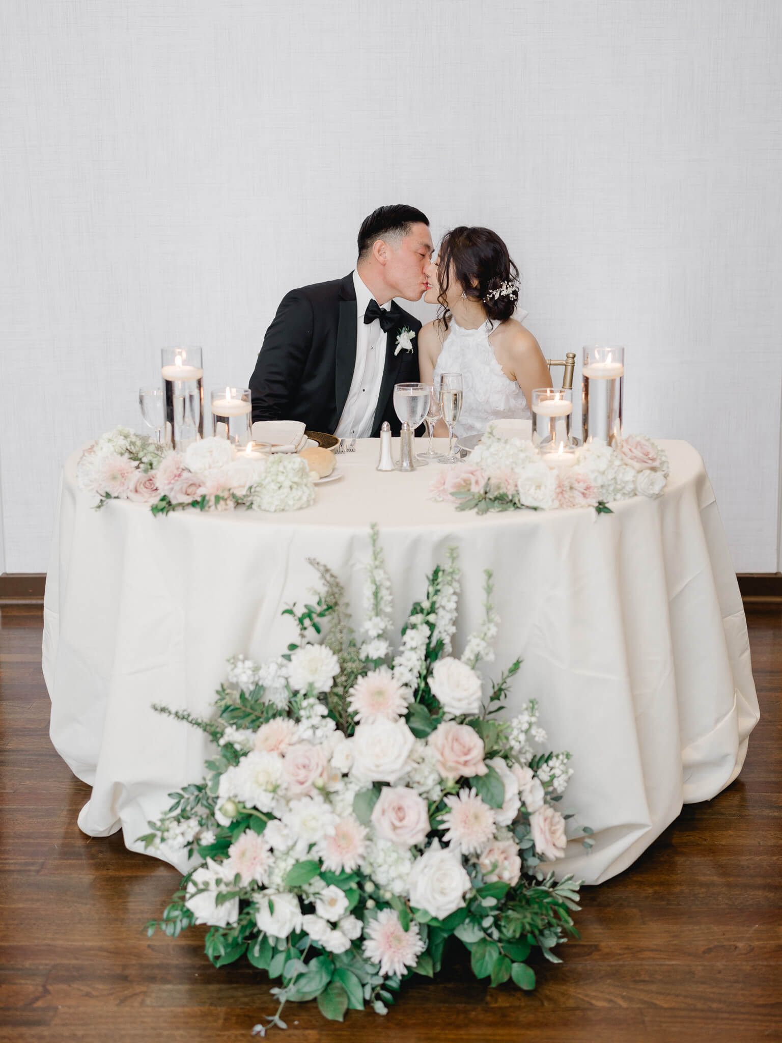 A bride and groom kissing at their sweet hear table.