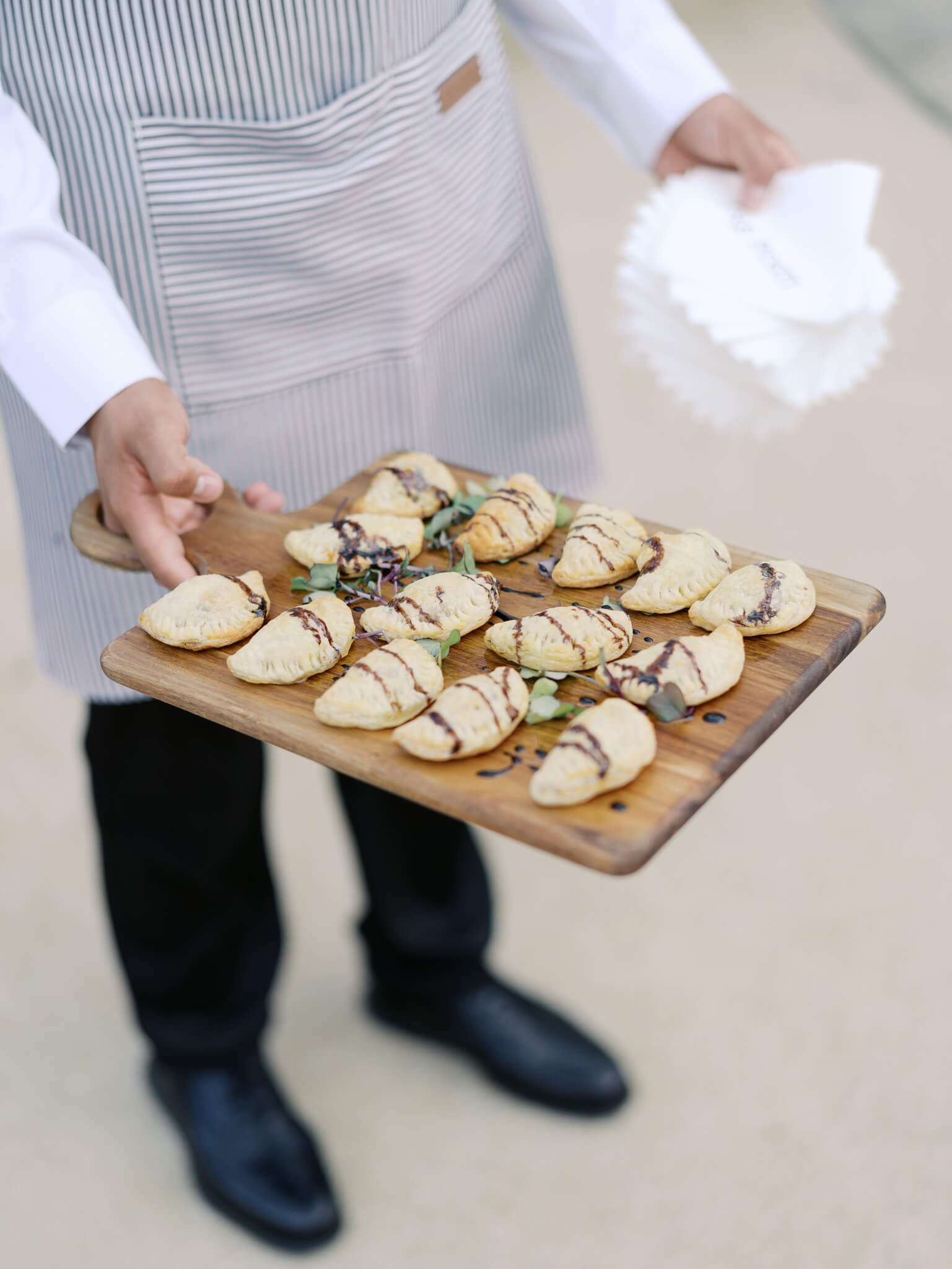 Closeup of appetizers being held on a wooden board during a cocktail hour.