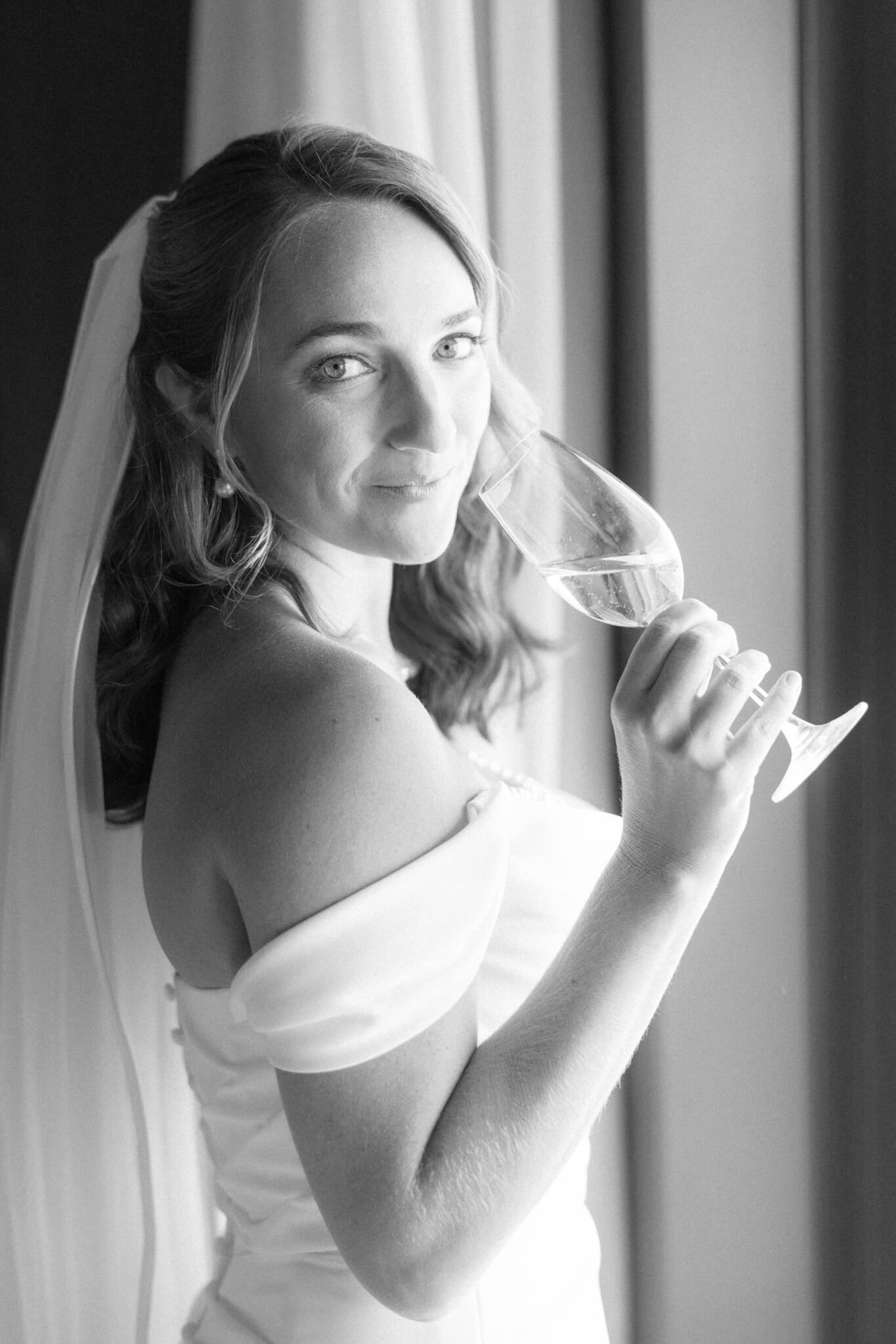 Black and white image of a bride sipping champagne.