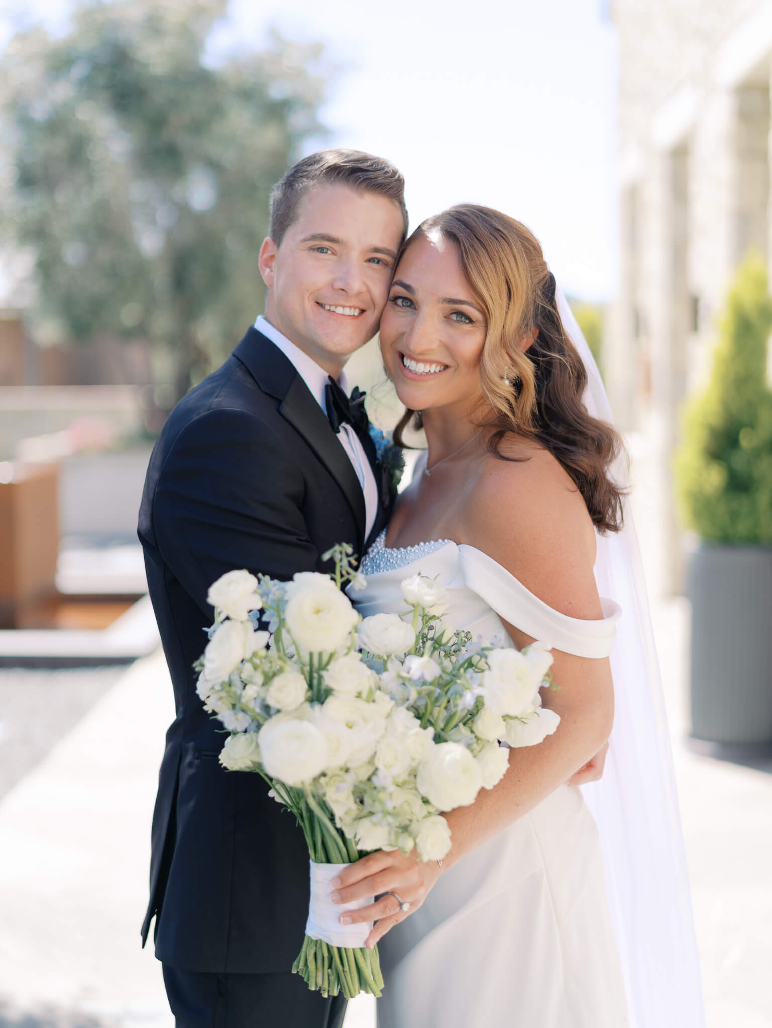 Closeup of a bride and groom smiling at the camera.