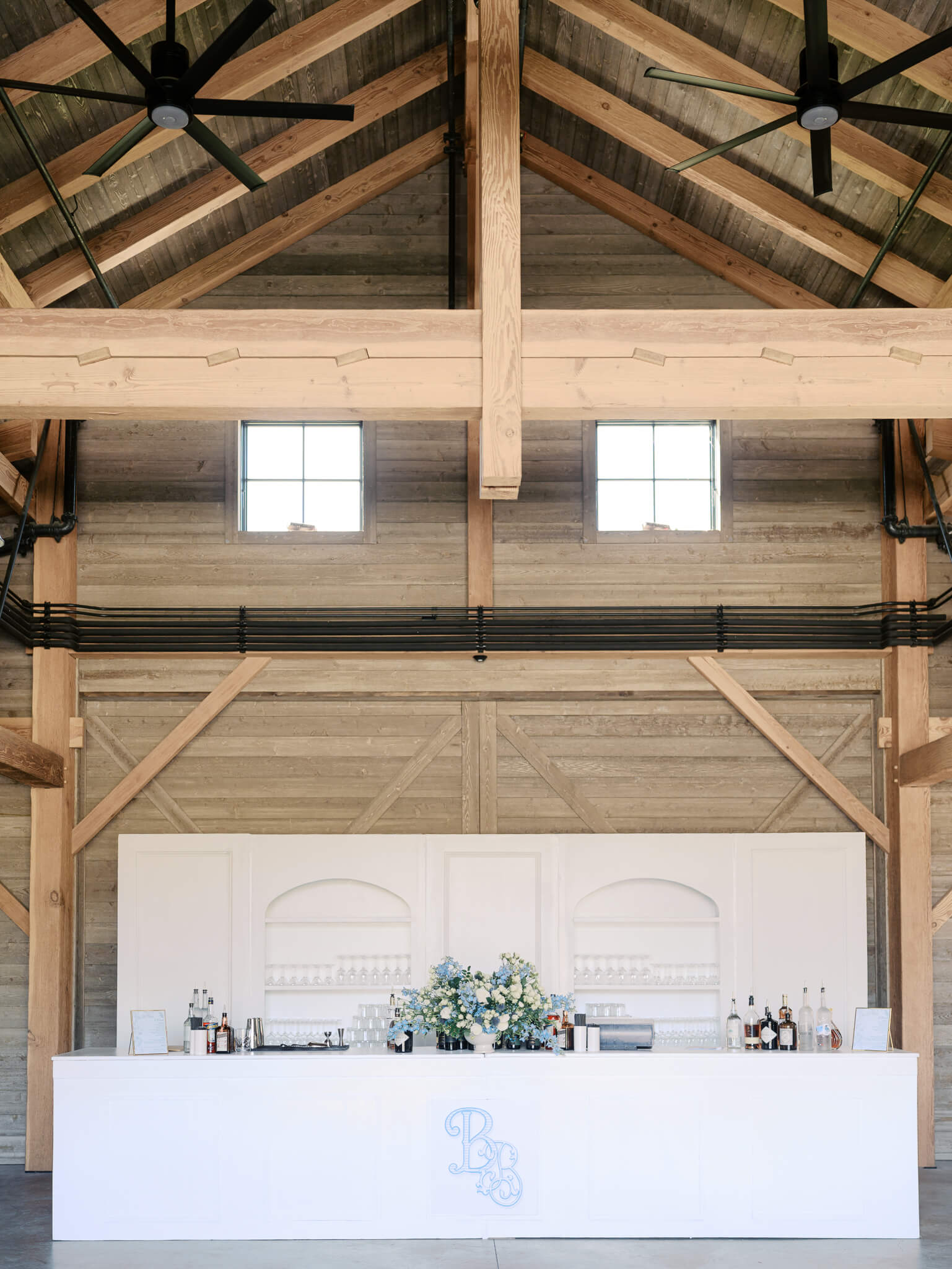 A white custom bar inside a barn at a destination wedding weekend.