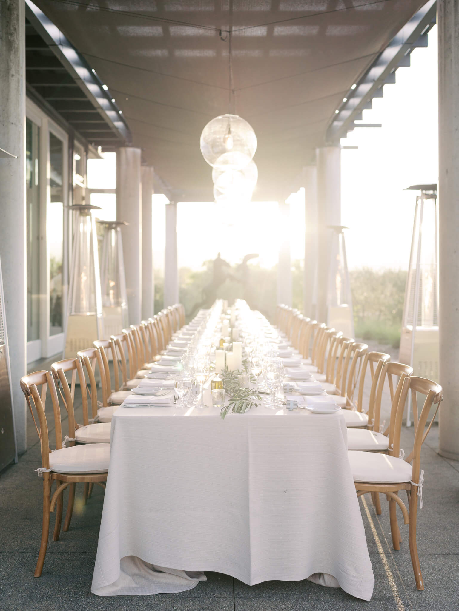 A long table set for a rehearsal dinner at a destination wedding during sunset.