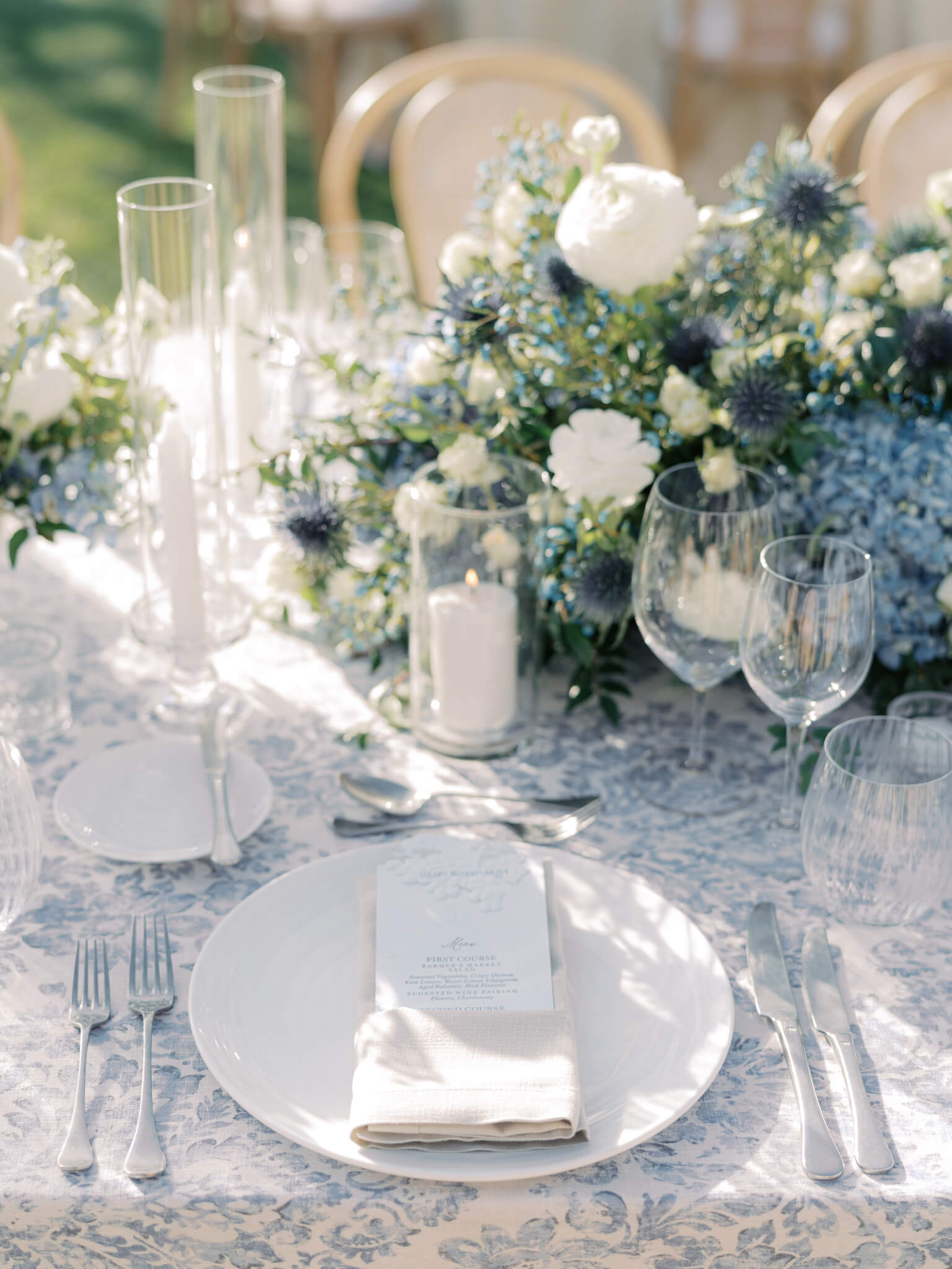 Close up of a table setting with blue, white and green color tones and clear candle holders.